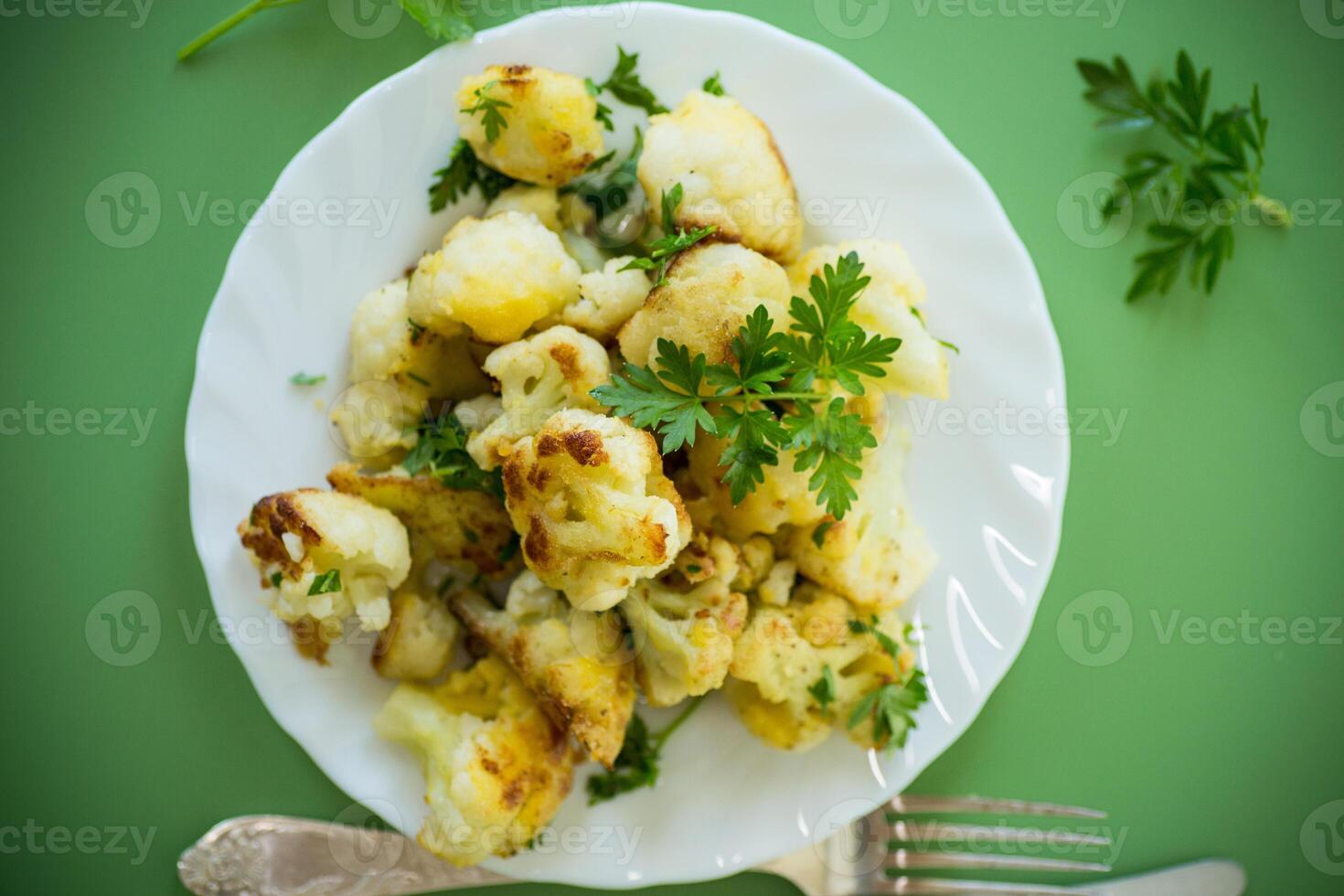 Vegetable dish of fried cabbage with aromatic spices on a green background . photo