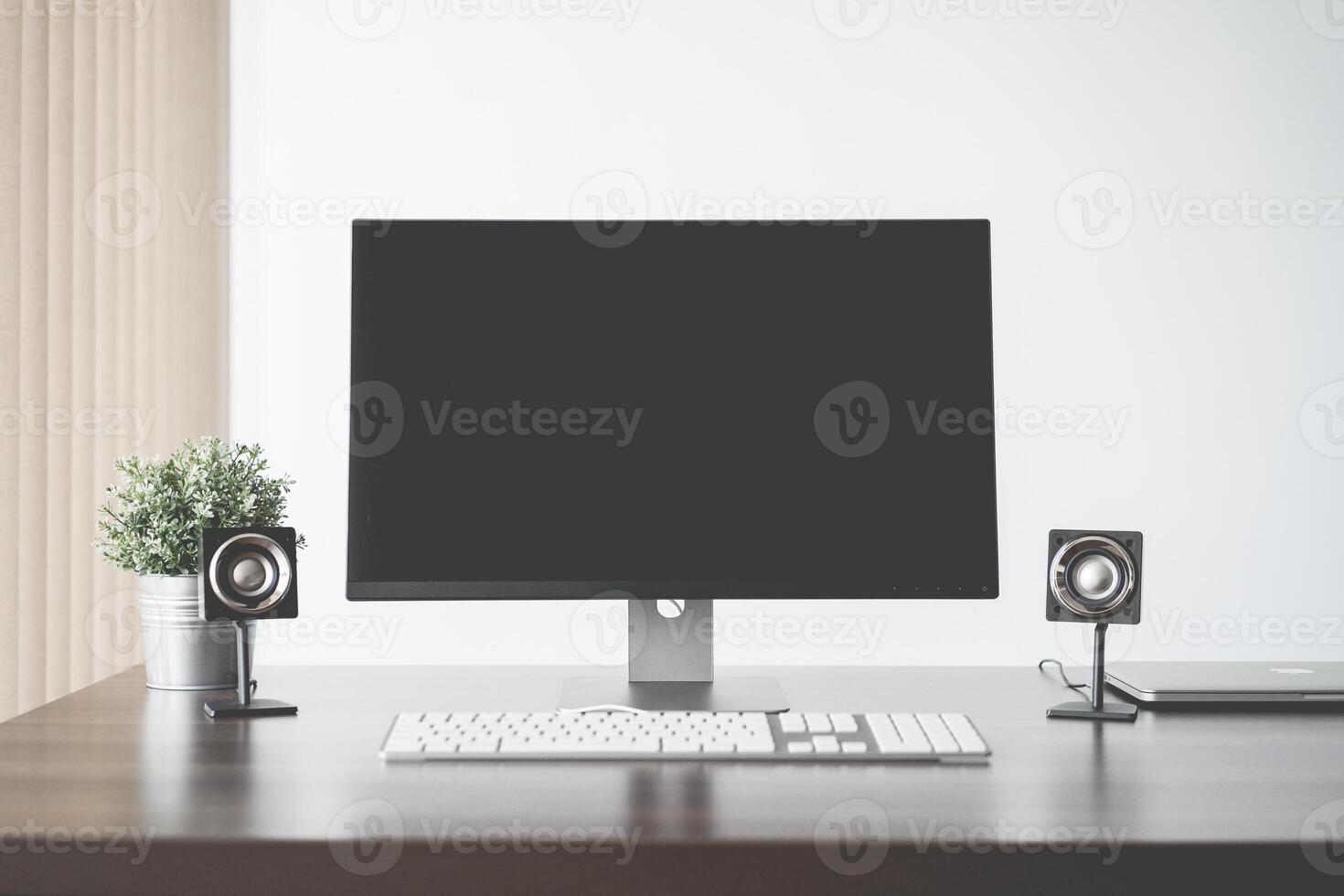 A desk setup with a computer monitor keyboard speakers and a potted plant against a white background photo