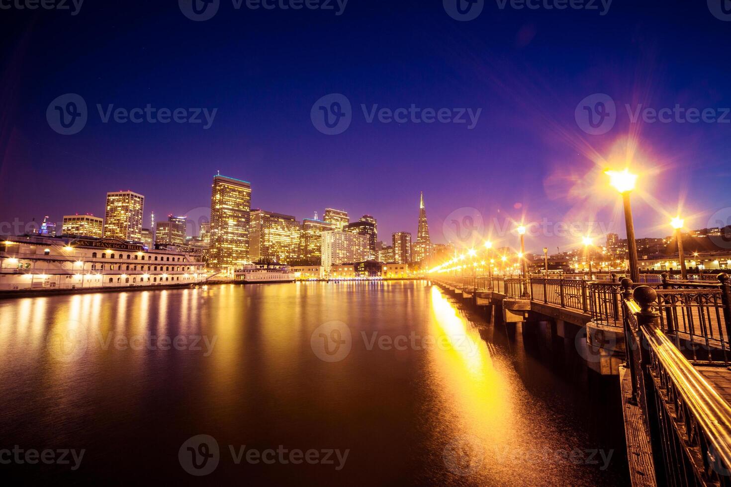 Cityscape view of san francisco at night with lights reflecting in the water from the pier side photo