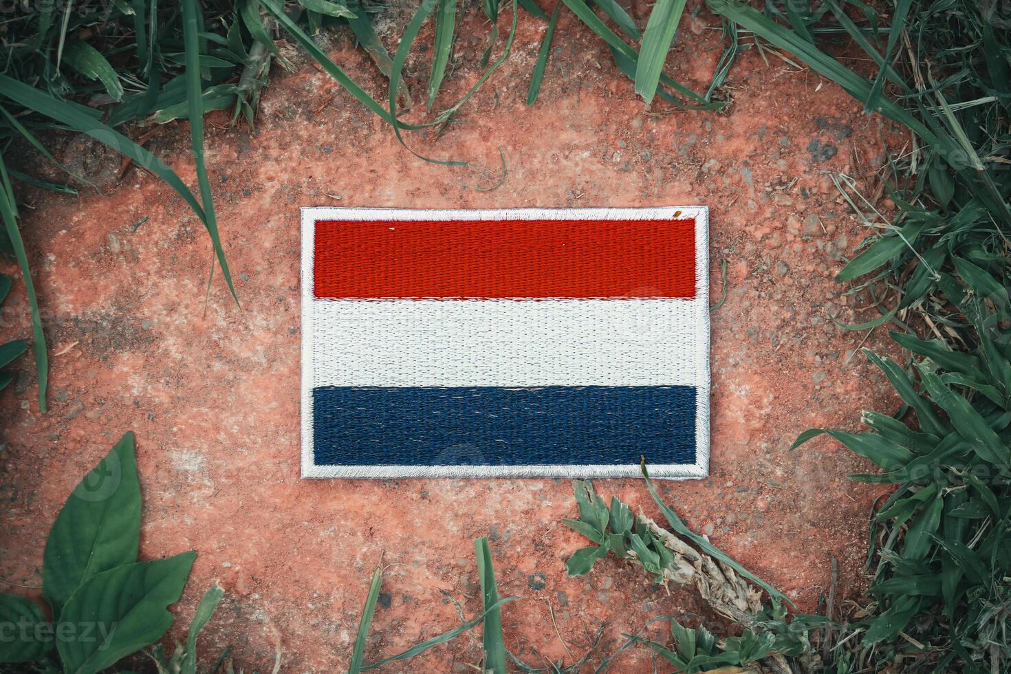 Top view of eco friendly Netherlands flag hand stitched with natural fabric, placed on ancient stone surrounded by leaves. Highlighting patriotism and sustainability in Europe. photo