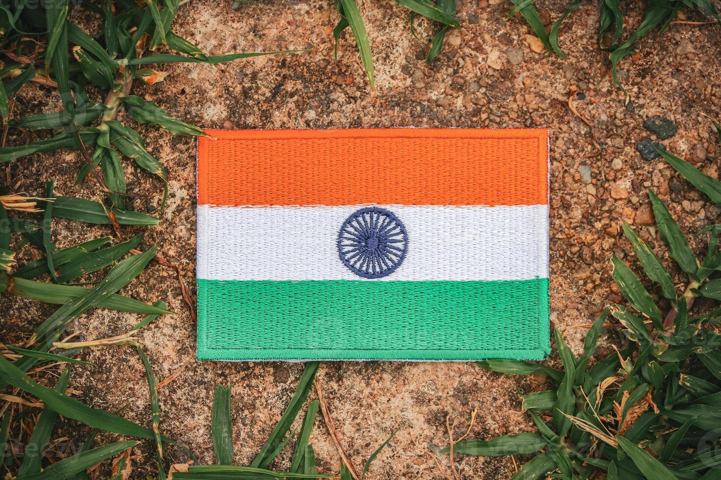 Top view of eco-friendly Indian flag made from hand-stitched fabric, placed on ancient natural stone surrounded by leaves and grass. Representing love for India, Asia. photo