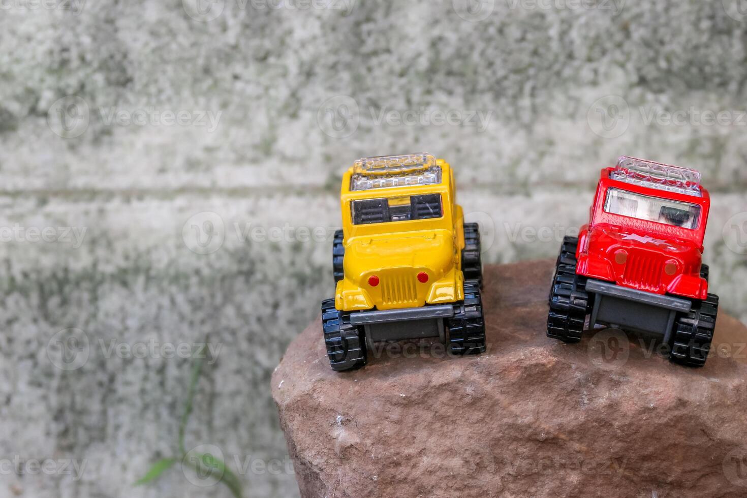 Creative miniature scene of two 4x4 pickup trucks, one yellow and one red, parked side by side on rugged brown rocks, simulating an adventurous journey. Space left on the left for text. photo