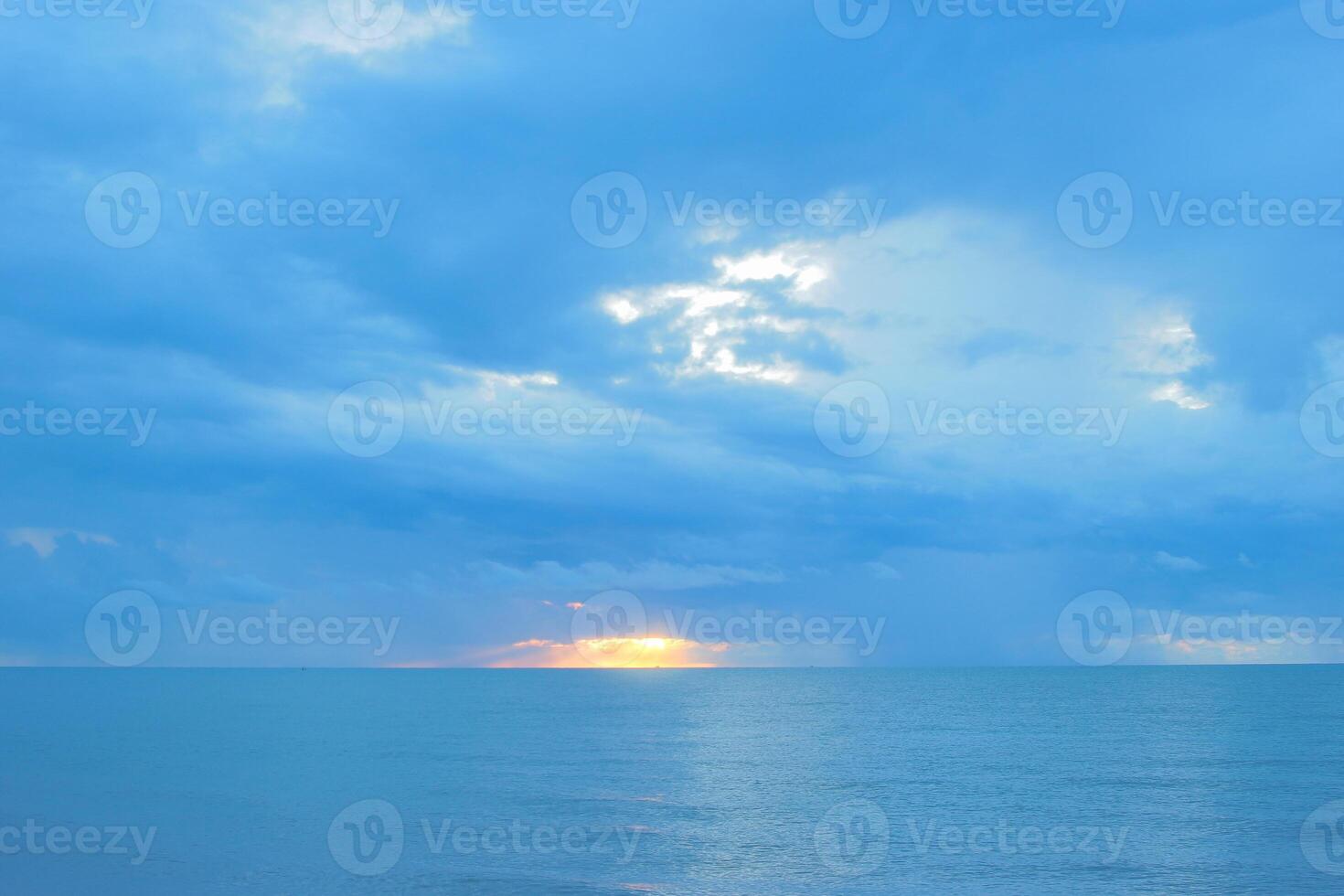 Beautiful seascape at sunrise with golden sunlight breaking through cloudy skies, casting warm light over the calm sea. Peaceful early morning ocean view, inspiring and serene. photo
