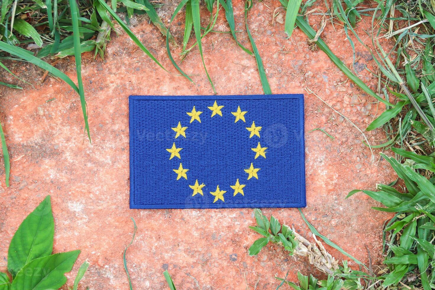 Eco friendly European Union flag, hand embroidered with natural fabric, placed on ancient stone surrounded by greenery. Promoting unity, sustainability, and environmental awareness in Europe. photo