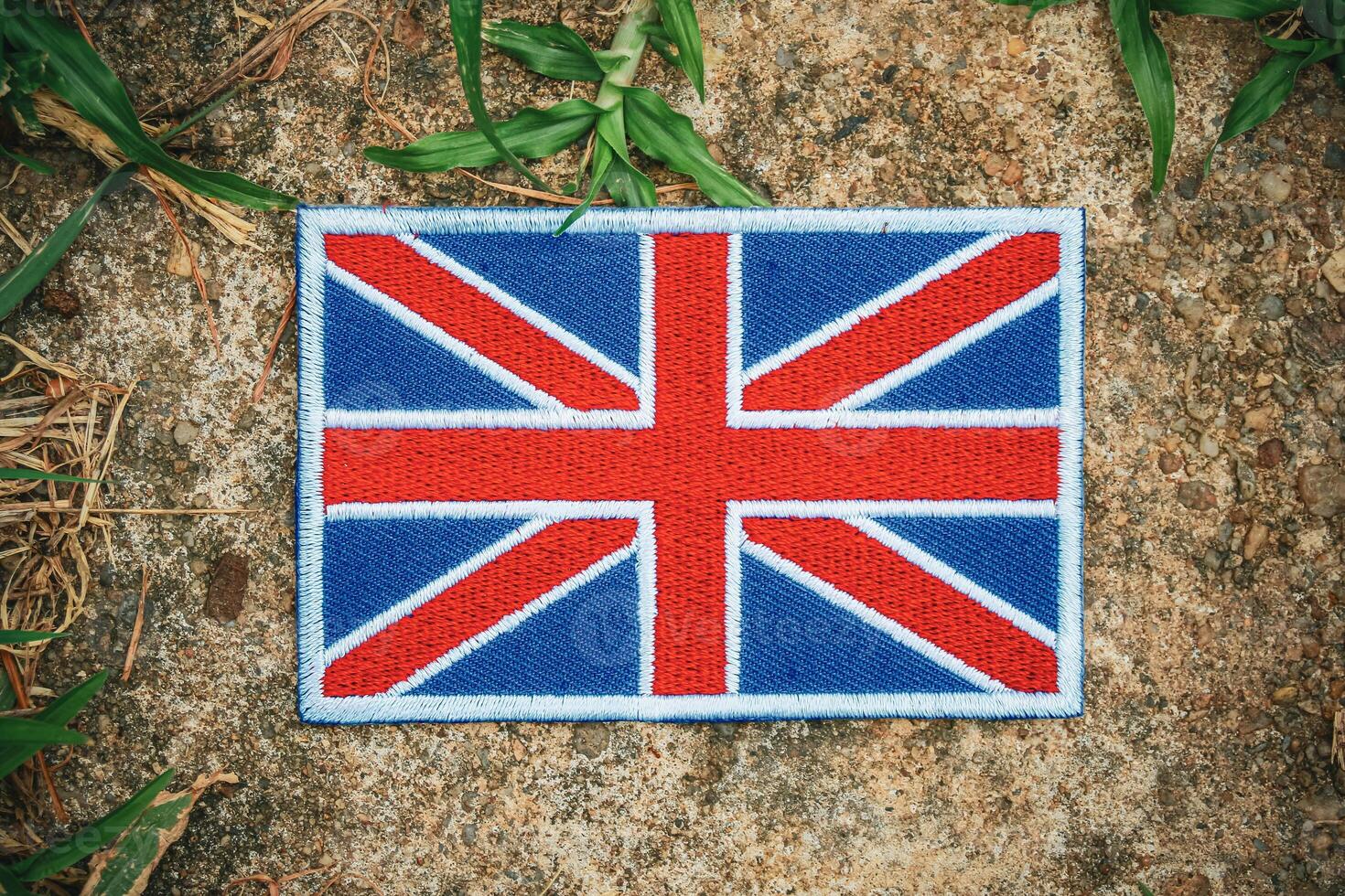 Top view Union Jack flag in eco style on natural stone with grass and leaves. A symbol of the UK s cultural pride and green awareness, ideal for Earth Day or climate themes. photo
