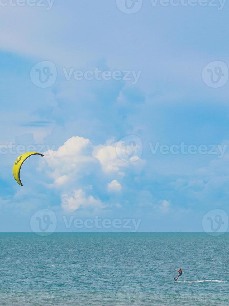 Vertical view of a solo kite surfer riding emerald waves at Hua Hin beach, Thailand. Summer fun with tropical skies and sparkling sea of Southeast Asia. photo