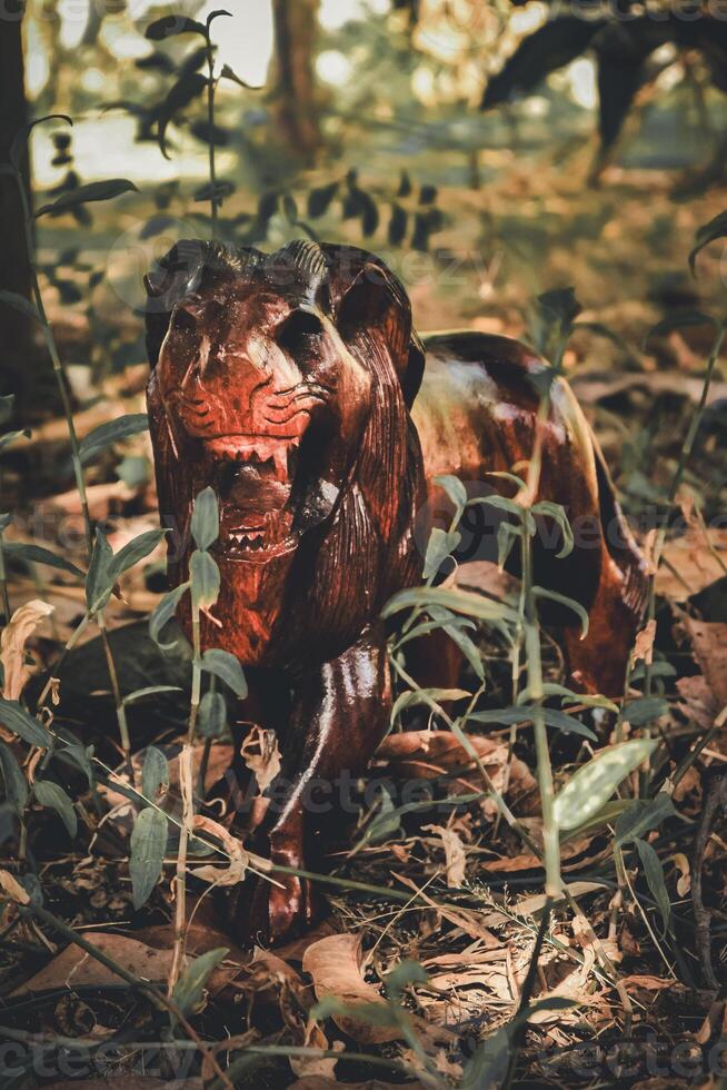 Wooden lion sculpture roaring in a forest-inspired setup. Natural sunlight creates dramatic shadows on the figure, combining wildlife art with realism against a soft background. photo