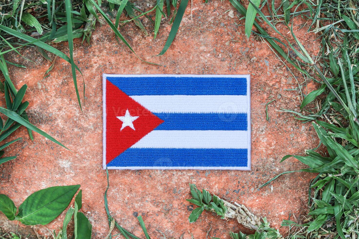 Top view of eco friendly Cuba flag made from hand stitched fabric, placed on aged stone with natural leaves around. Symbol of national pride and sustainability in the Caribbean. photo
