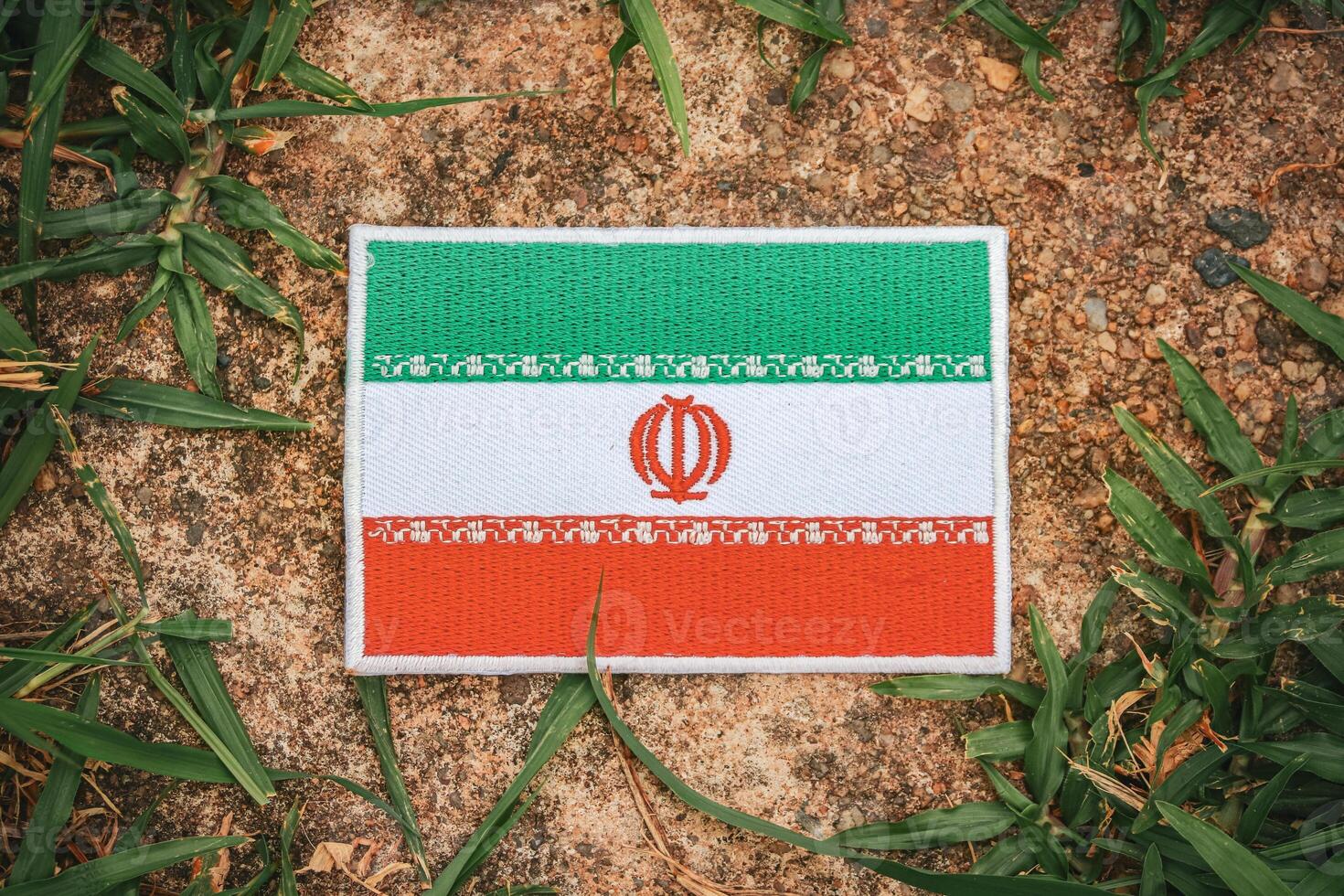 Top view of eco-friendly Iran flag, hand-stitched from natural fabric, placed on ancient stone with green leaves. Highlighting sustainability in Asia s Middle East region. photo