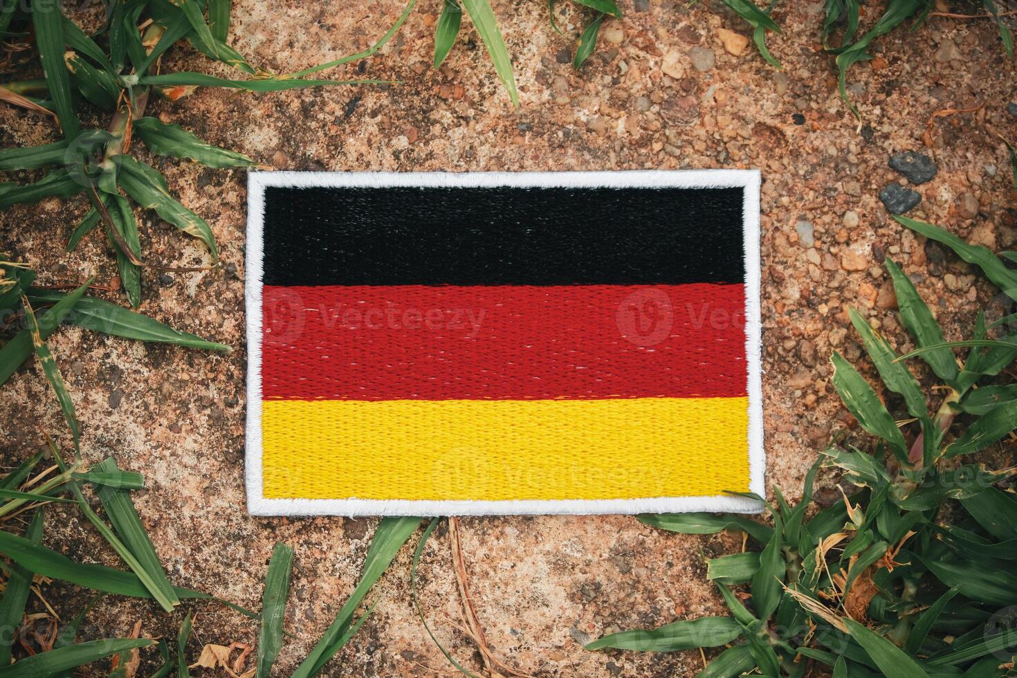 Eco-style German flag made of embroidered fabric on natural rock with leaves and grass. Central Europe theme, ideal for Earth Day, climate change, and green campaigns. photo
