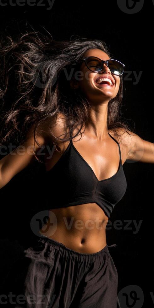 A woman in a black top and sunglasses dancing photo