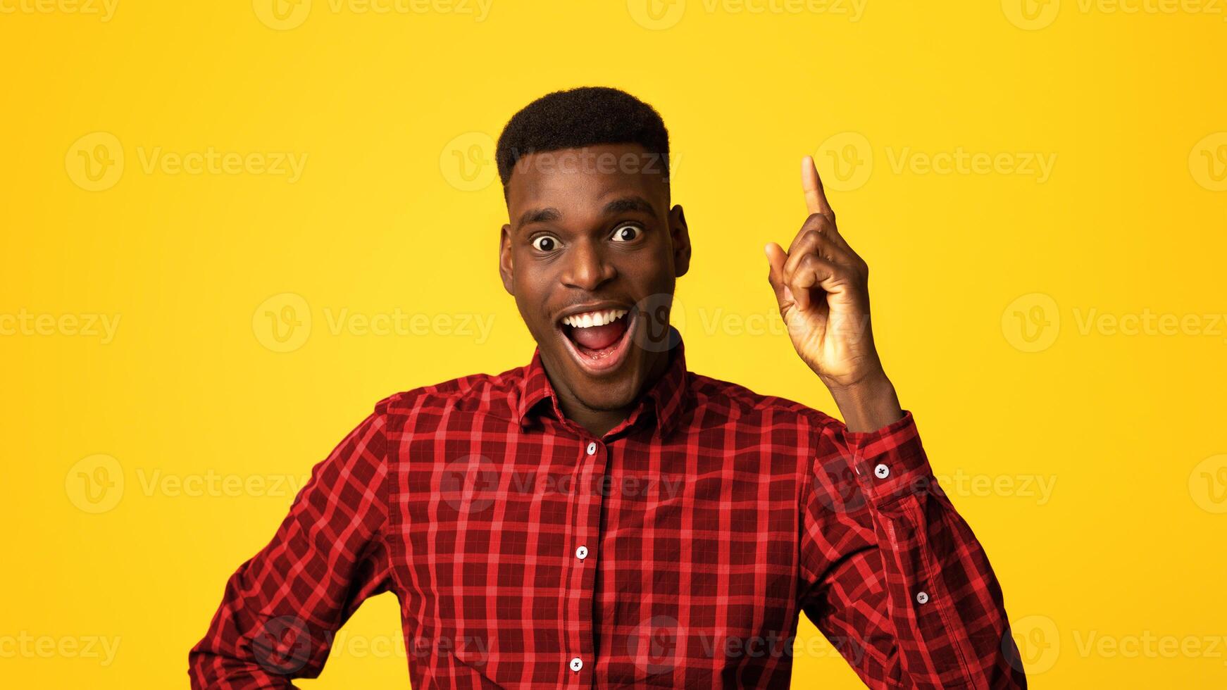 Great Idea. Excited African American Guy Pointing Finger Up And Looking At Camera, Having Inspirational Eureka Moment, Funny Young Man In Checkered Shirt Standing Over Yellow Background, Copy Space photo