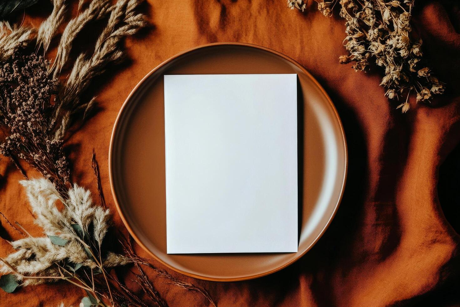 Rustic Table Setting With Dried Flowers and Blank Card on Orange Fabric Background photo