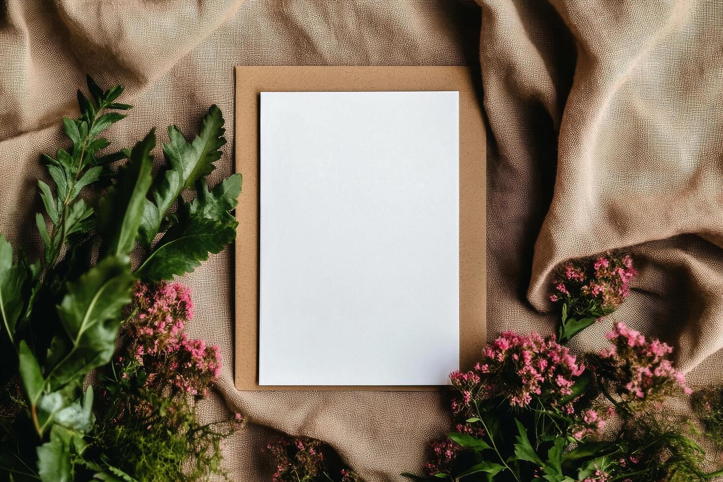 Blank Paper Surrounded by Fresh Greenery and Blooms on a Textured Fabric Background photo