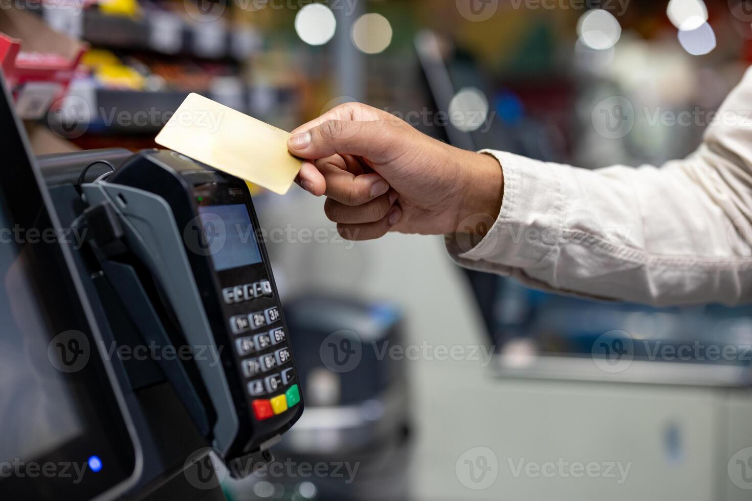 A hand holding a credit card over a payment terminal during a purchase in a store. Contactless payment concept. photo