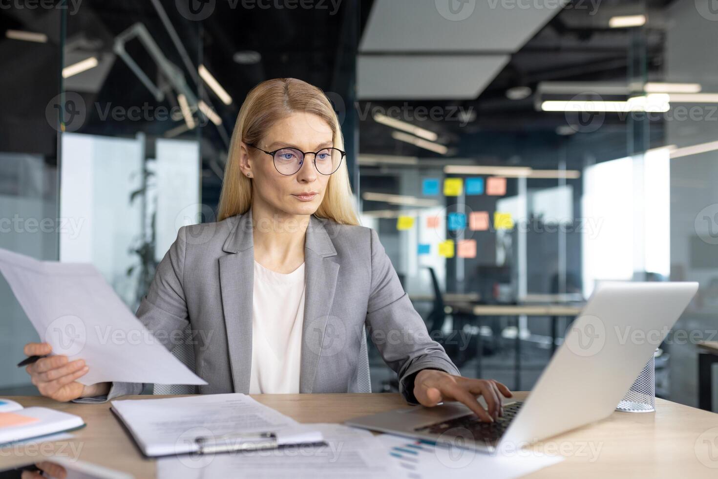 A businesswoman works on a laptop in a modern office, reviewing documents while working. photo