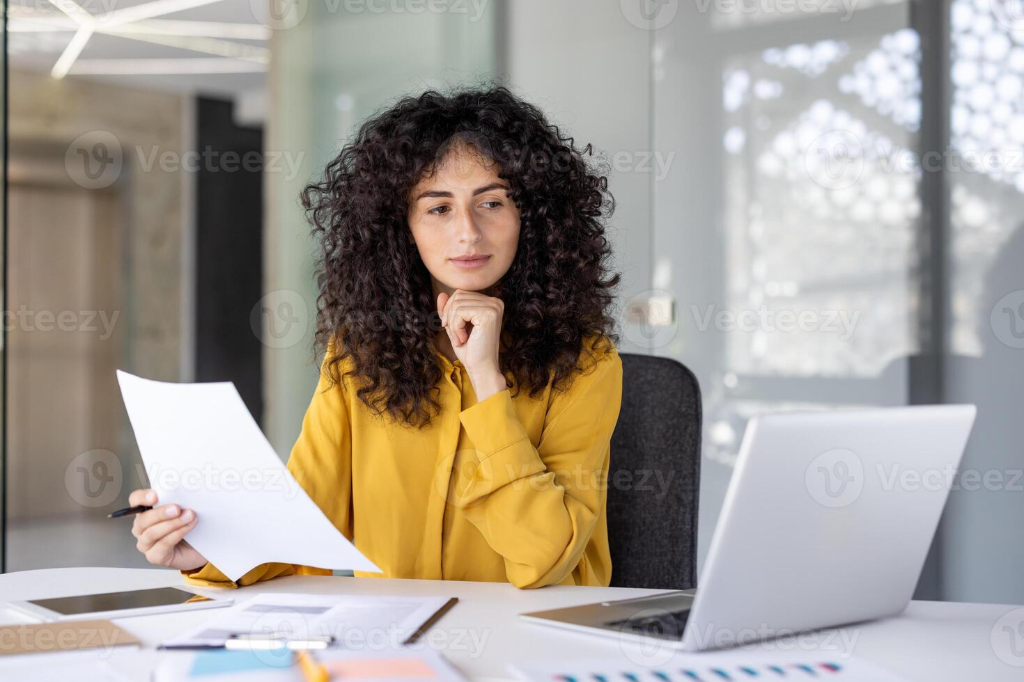 A thoughtful accountant reviews paperwork in a modern office setting, looking for discrepancies and ensuring compliance photo