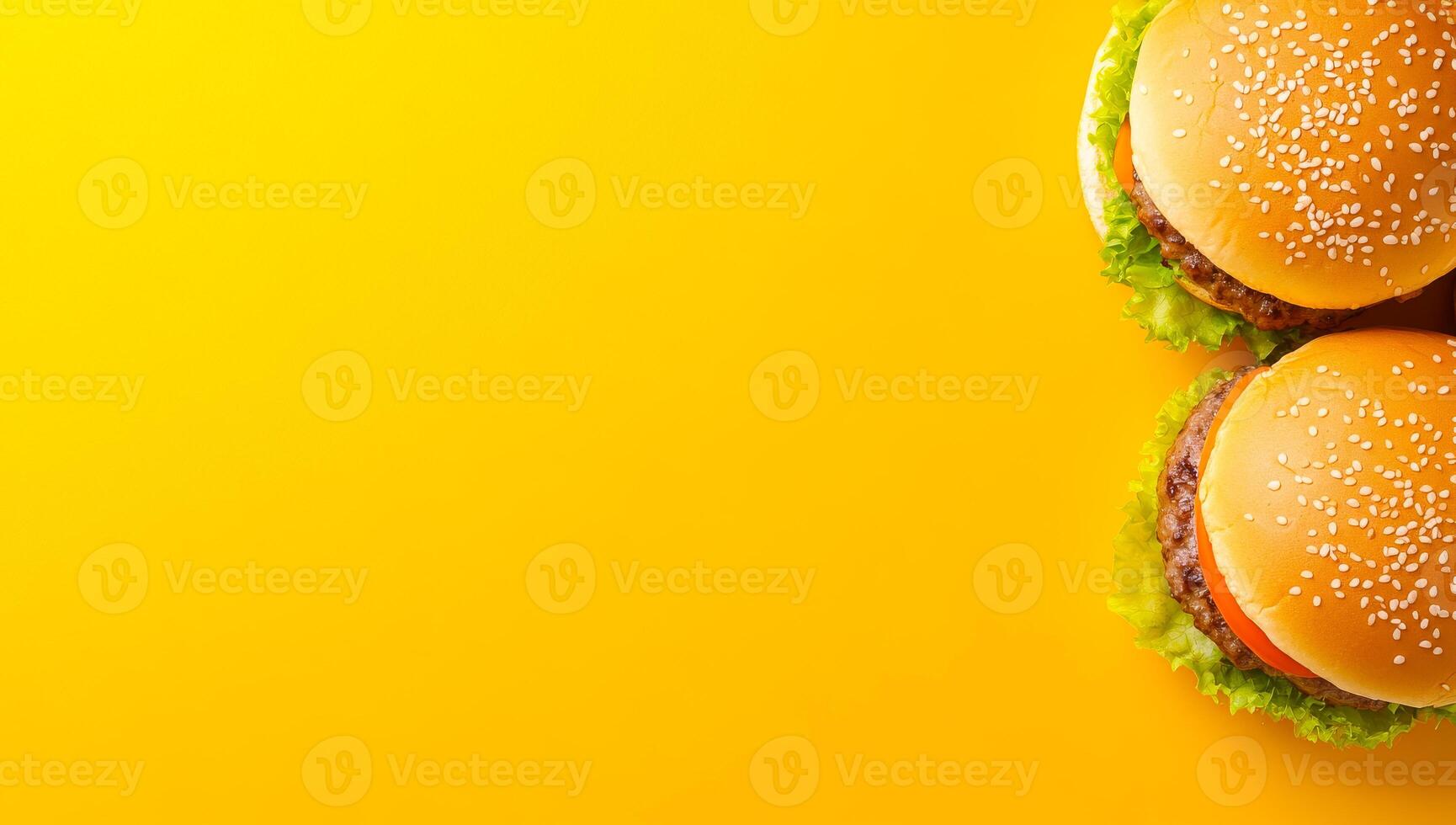 Burgers on a yellow backdrop. Two mouthwatering burgers with sesame seeds sit on fresh lettuce against a vibrant yellow backdrop. photo