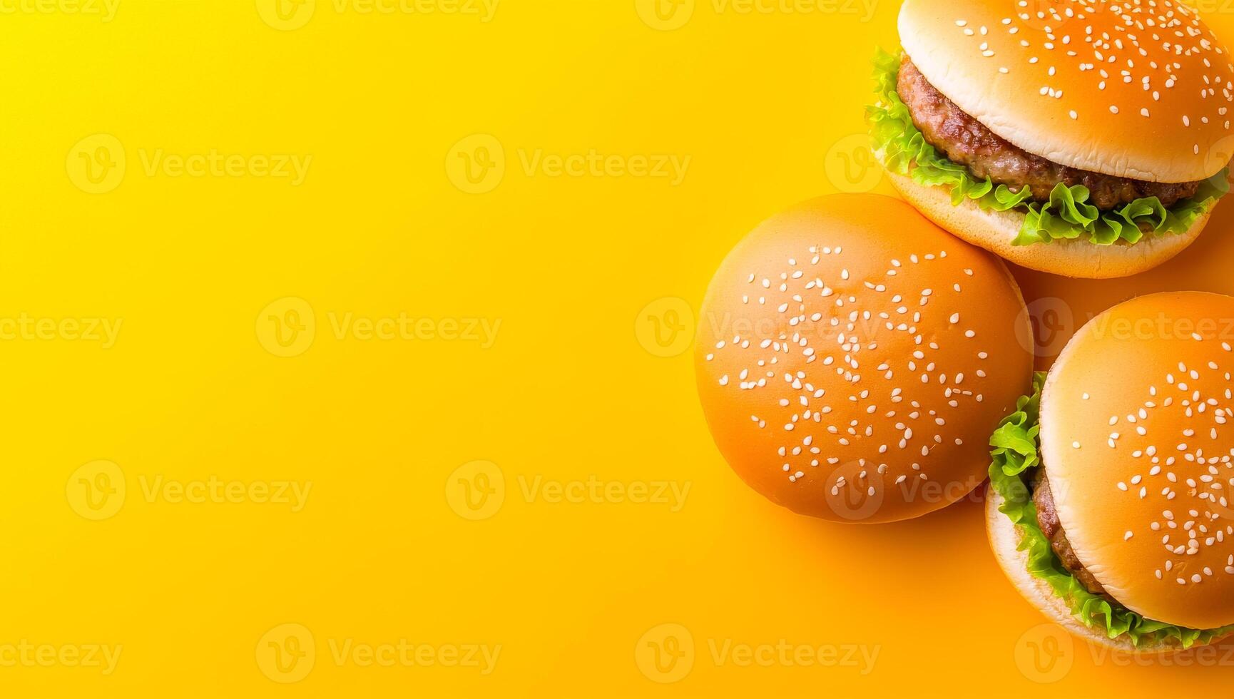 Yummy burgers on yellow. Two appetizing burgers topped with lettuce sit on a bright yellow background, showcasing a vibrant food presentation. photo