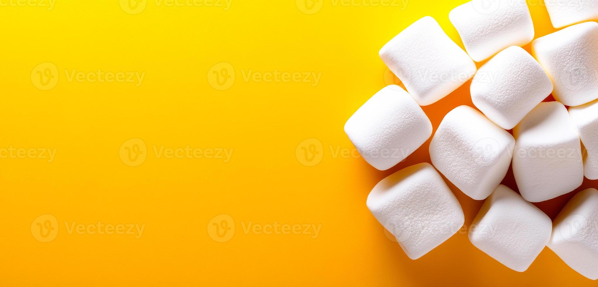 Soft marshmallows on a bright backdrop. A collection of fluffy white marshmallows is positioned on a vibrant yellow background, creating a cheerful display. photo