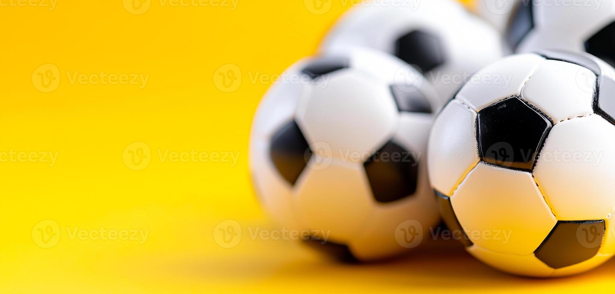 Soccer balls on yellow. Several soccer balls are arranged closely on a vibrant yellow background, highlighting their black and white design. photo