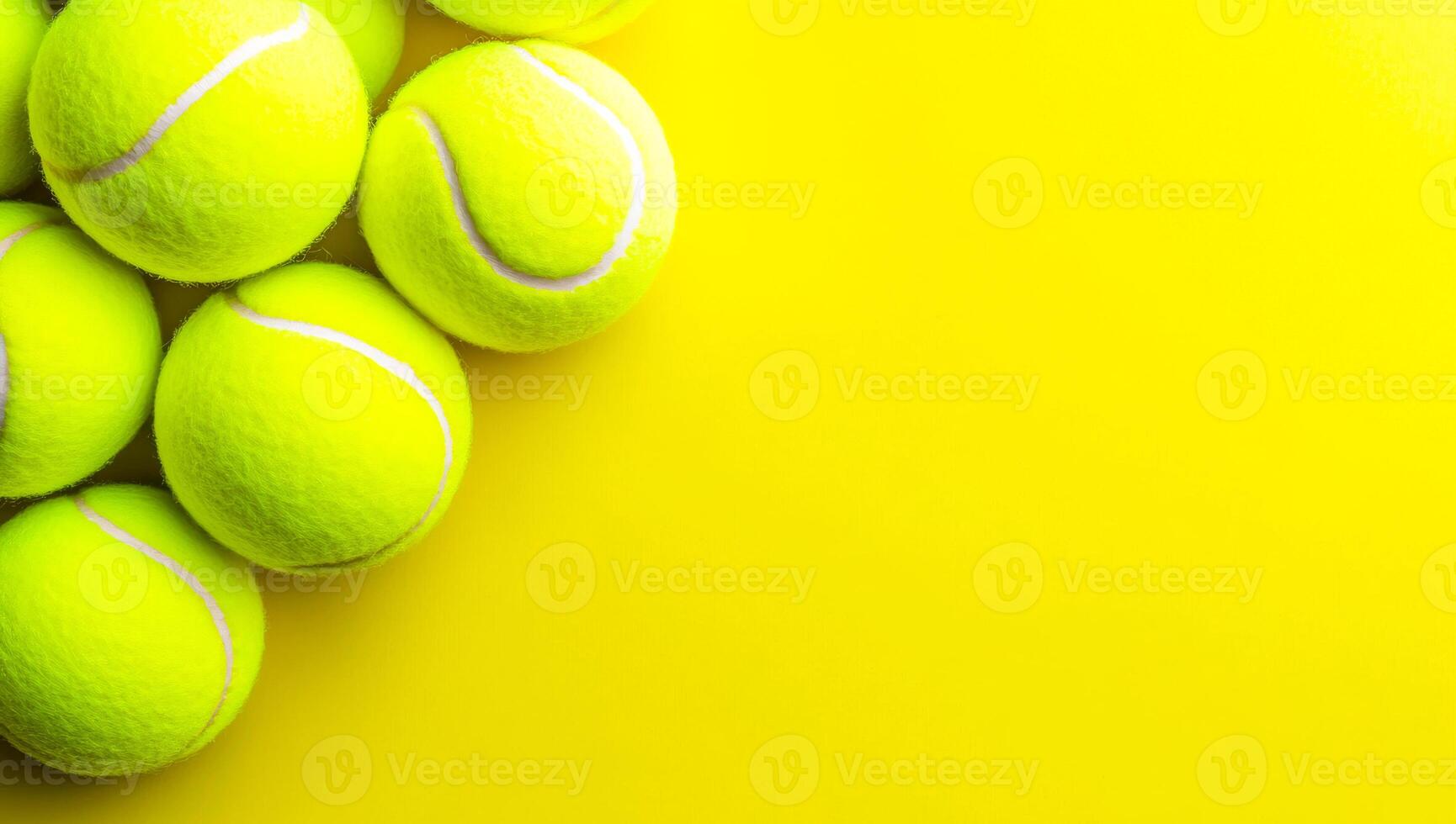 Yellow tennis balls on vibrant court. Several bright yellow tennis balls are arranged on a vivid yellow background, showcasing their texture and color. photo
