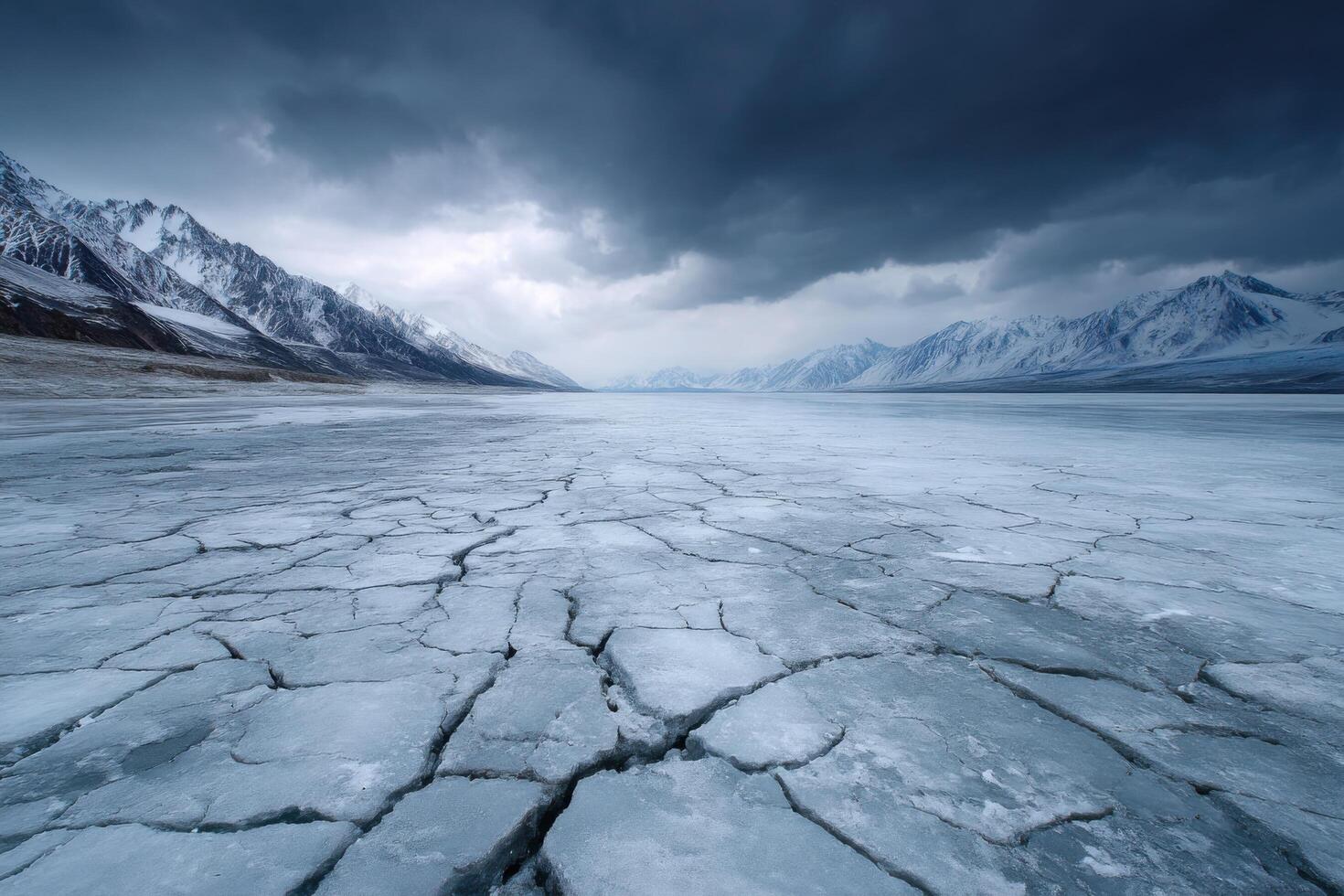 Frozen Lake in the Mountains A Dramatic Winter Landscape. The vast expanse of cracked ice reflects the moody sky and snow capped peaks, creating a breathtaking, serene scene. photo