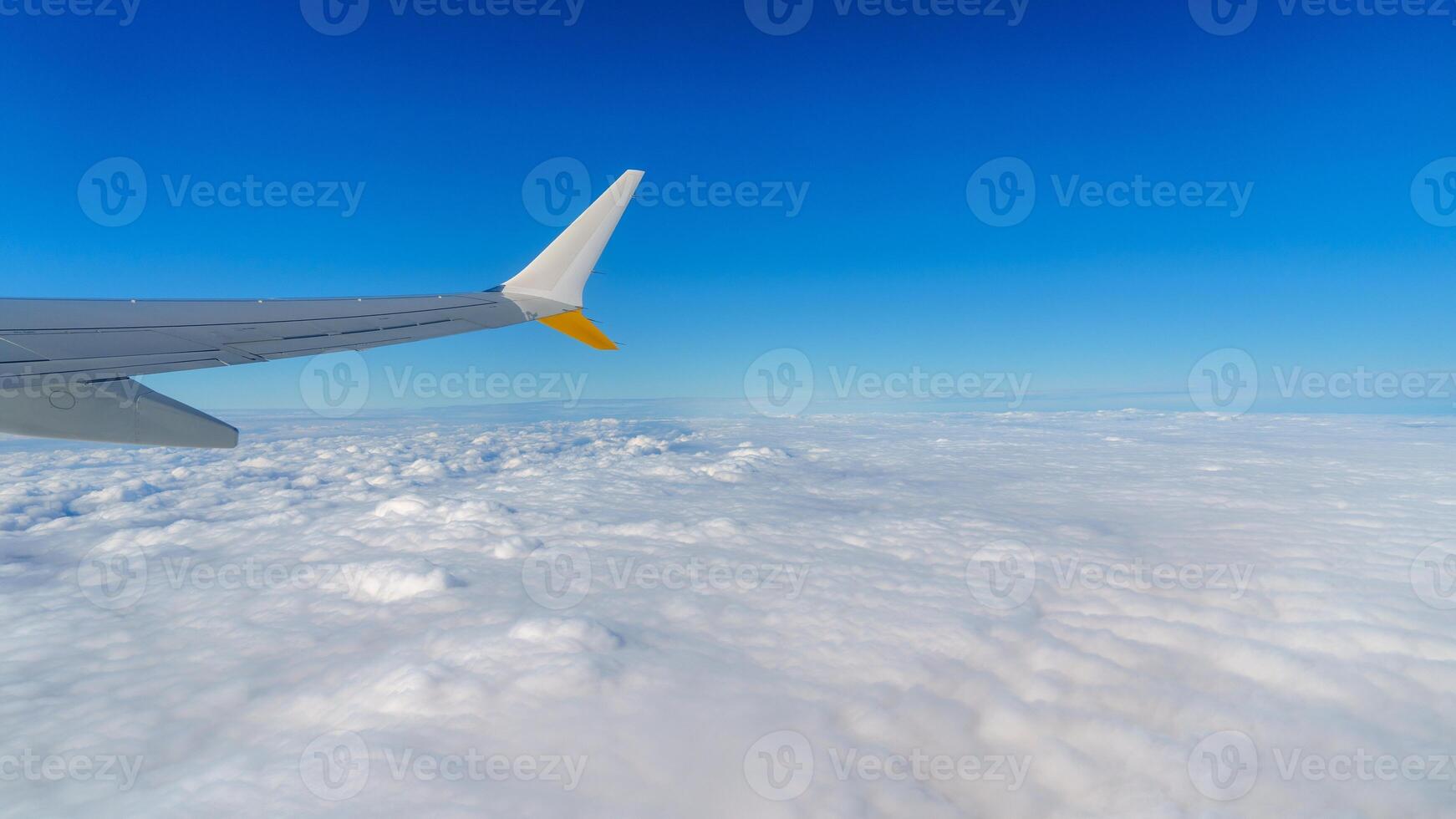 Stunning aerial view from an airplane window, featuring the aircraft s wing gliding above a sea of fluffy white clouds set against a bright blue sky. Perfect for travel and exploration. photo