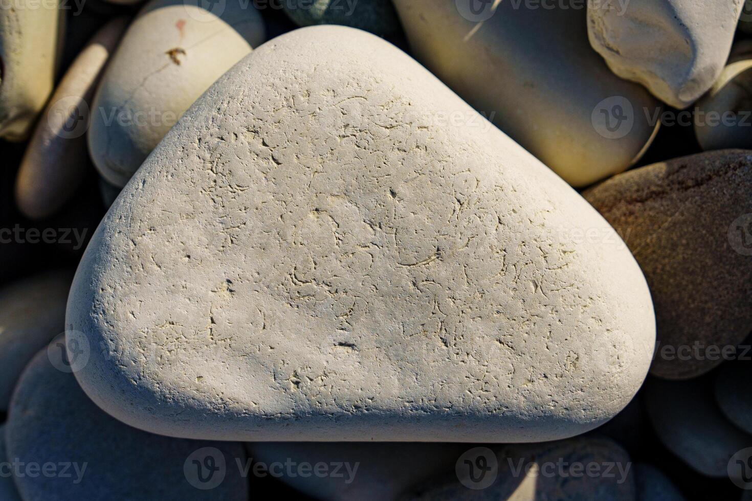 Discover the tranquility of a smooth, light-colored beach stone in this close-up image. Its natural texture and shape offer a calming touch, ideal for various design and creative projects. photo