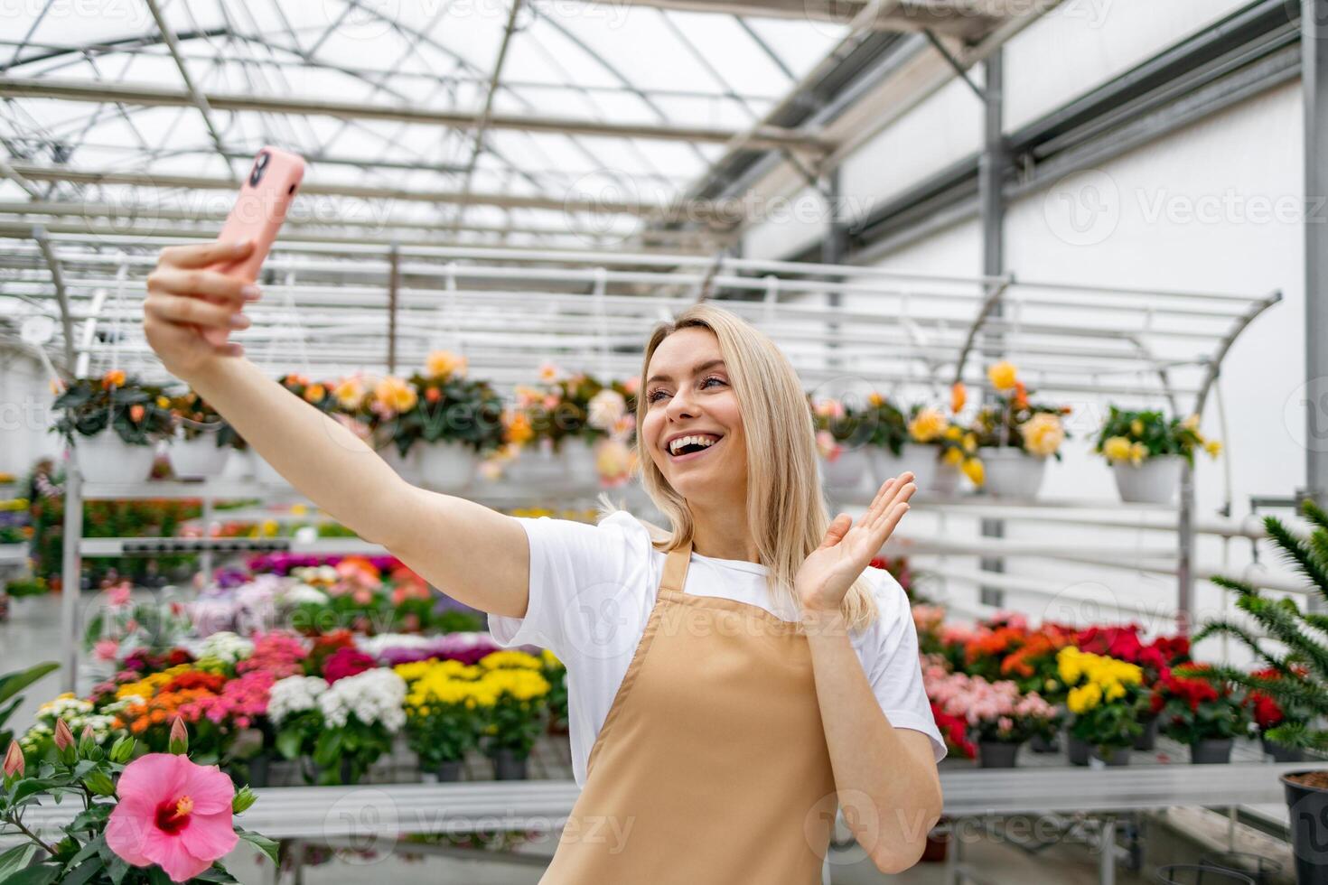 A cheerful Caucasian woman takes a selfie in a flower shop, surrounded by various colorful plants. photo