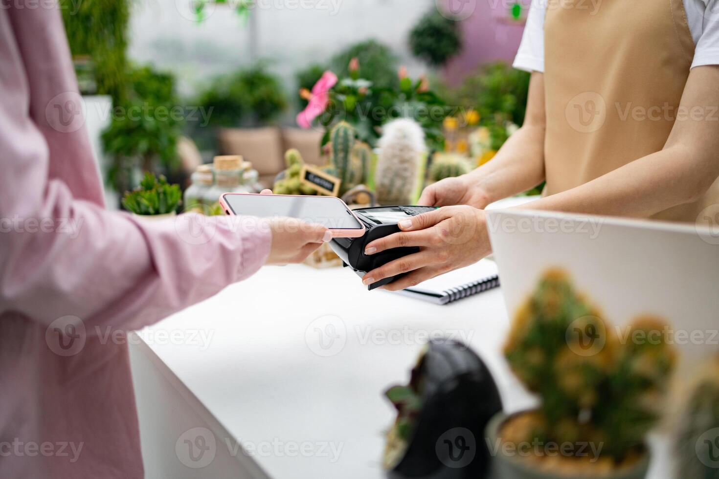 A customer uses their phone to make a contactless payment at a florist shop's checkout counter, a new way to pay. photo