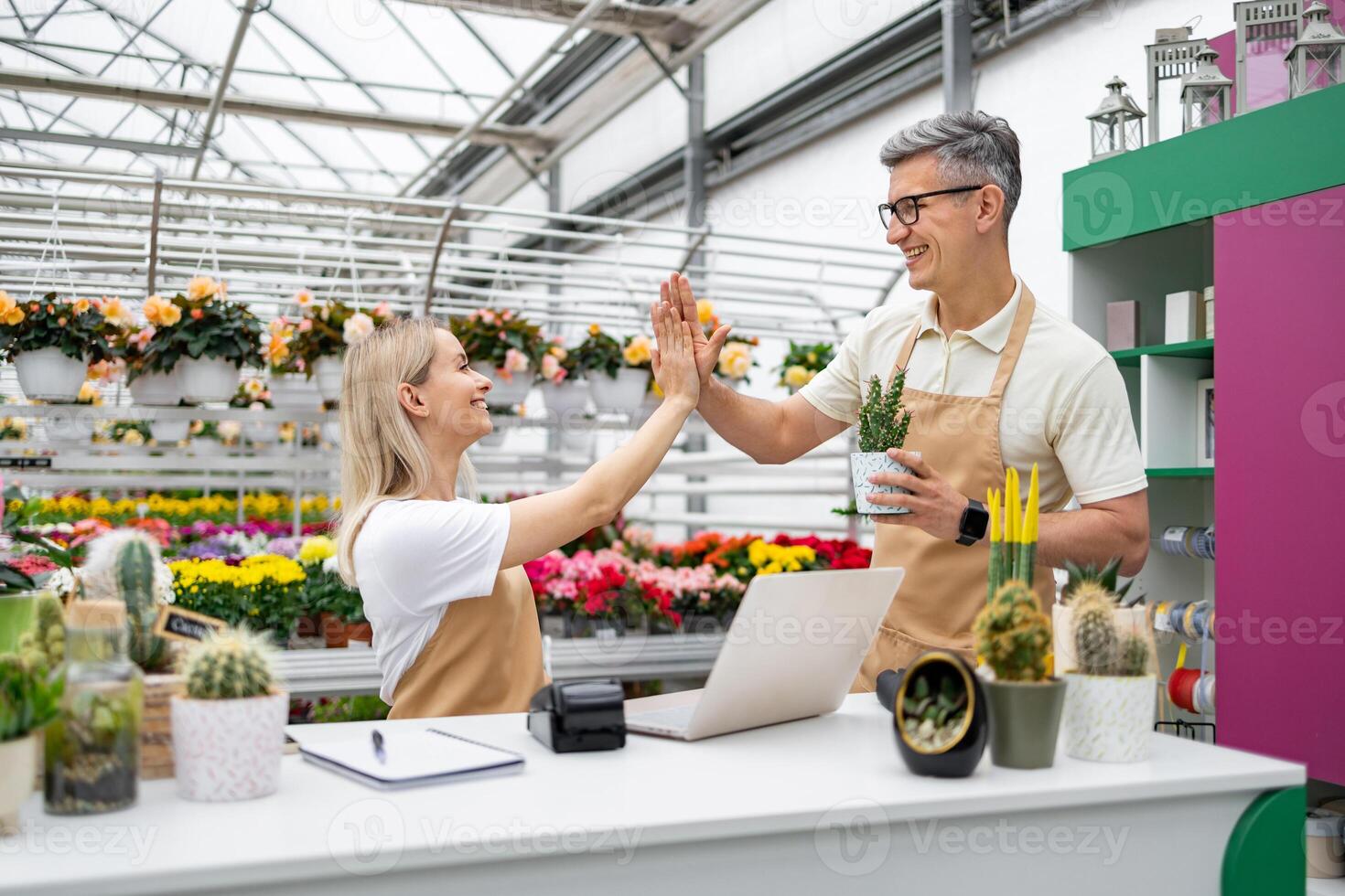 A Caucasian florist shop employee and a customer give each other a high five after a sale, a happy gesture. photo