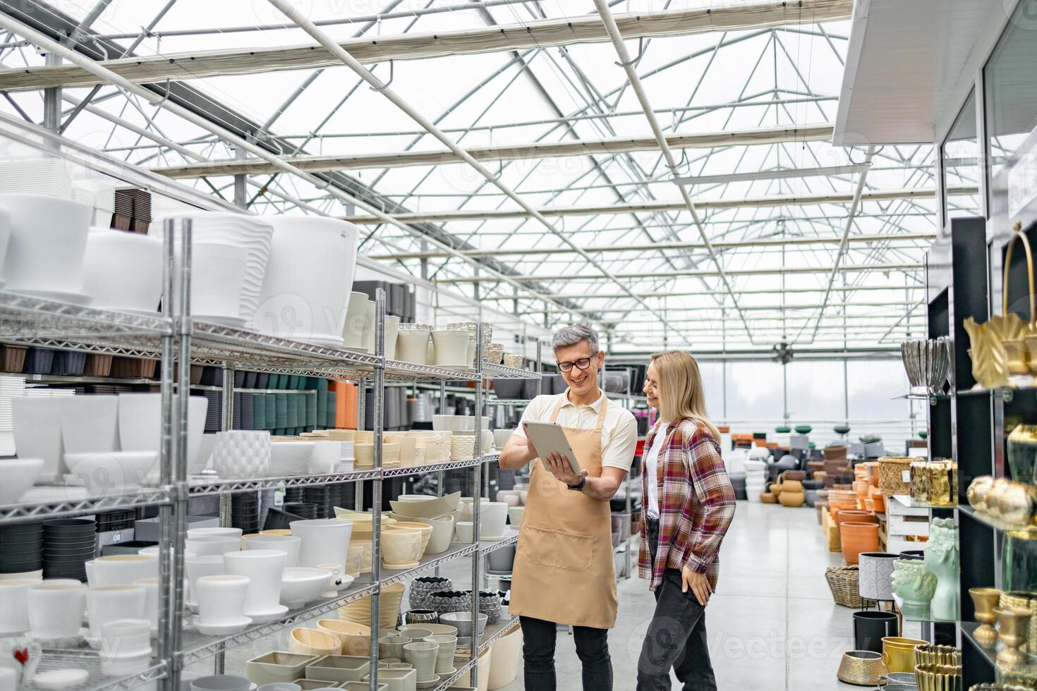 A store employee assists a female customer in a garden shop with a wide selection of flowerpots. photo
