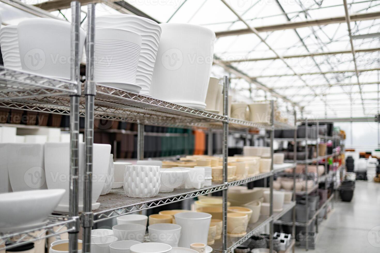 A collection of flowerpots displayed on shelves inside of a plant shop, showing variety in shape and size. photo