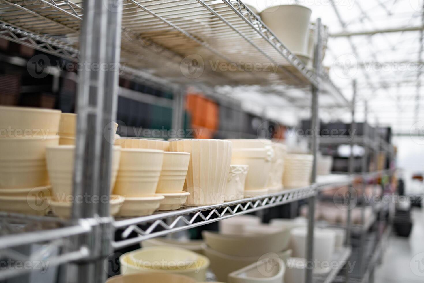 Flowerpots of various sizes are displayed on shelves in a garden center, ready for sale. photo