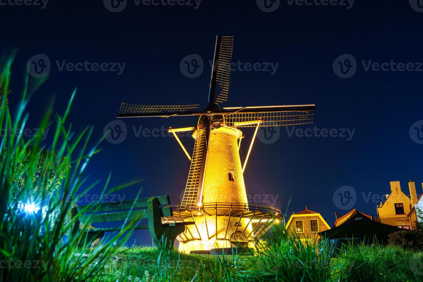 Beautiful old windmill standing tall and illuminated by colorful lights during the night in Zierikzee, a historic town in the Netherlands, creating a stunning and picturesque scene. photo