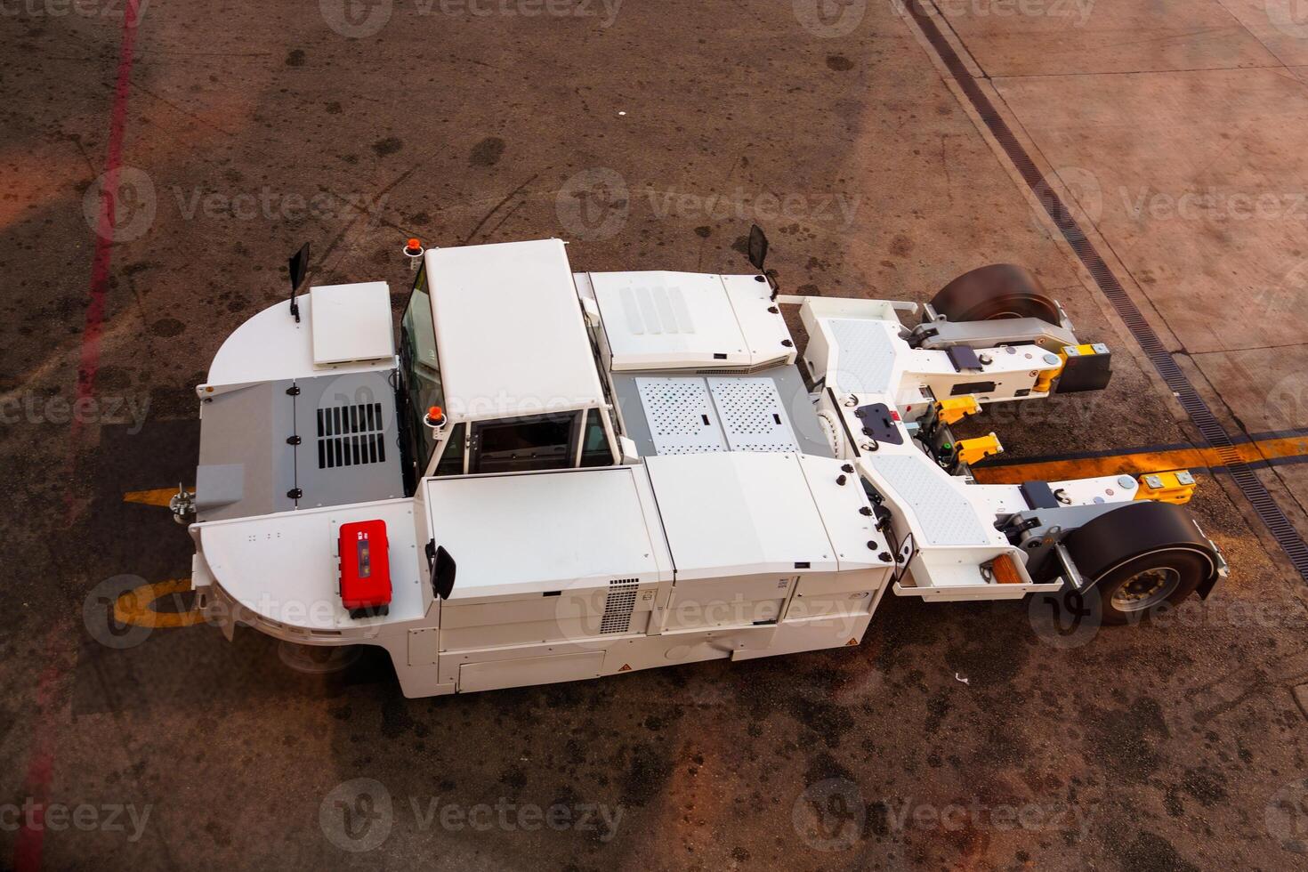 A high-angle view shows a white aircraft towing tractor on the airport apron, crucial for maneuvering aircraft. Essential ground support equipment ready for operation in the aviation industry. photo