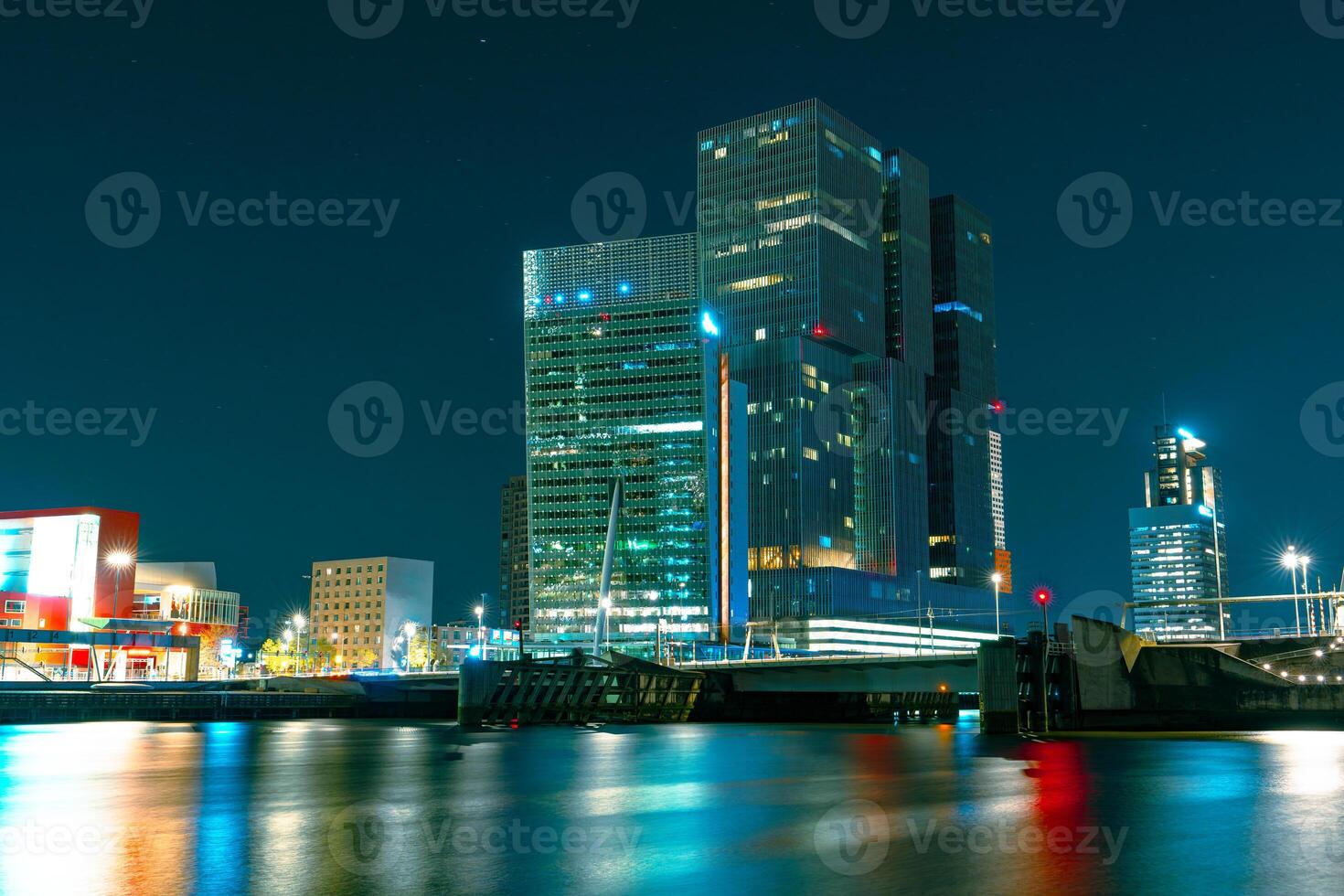 A stunning nocturnal view of Rotterdam's high-rise architecture standing tall against the backdrop of the starry night sky, creating a magnificent and captivating urban scenery. photo
