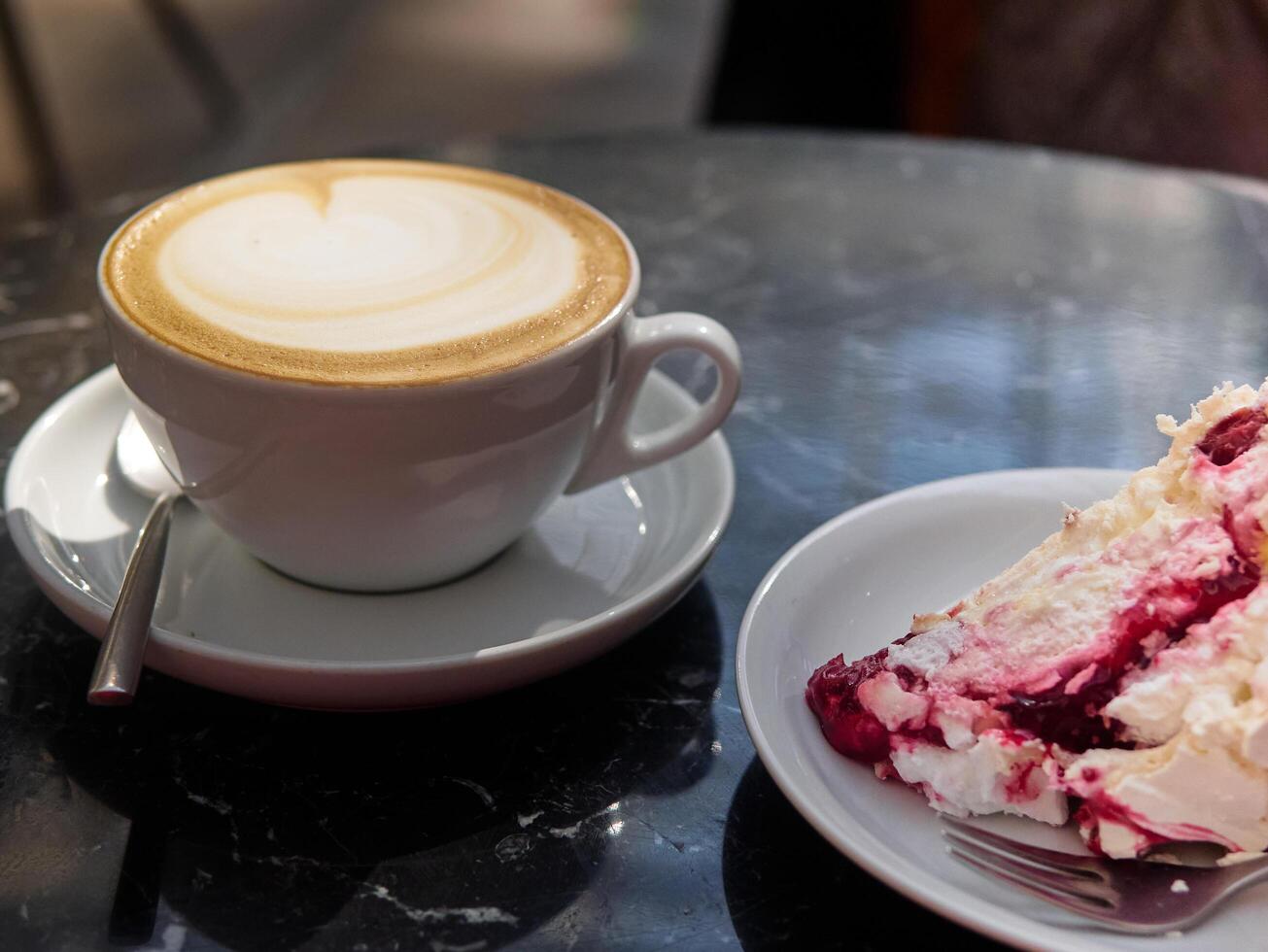 Cup of coffee sits on a saucer next to a slice of cake photo