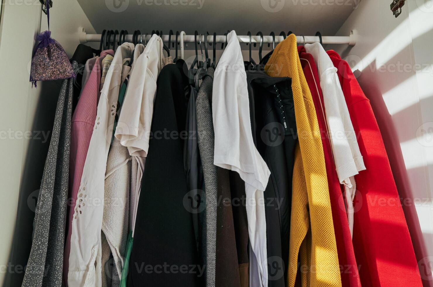 Closet full of clothes, including a red sweater and a white shirt photo