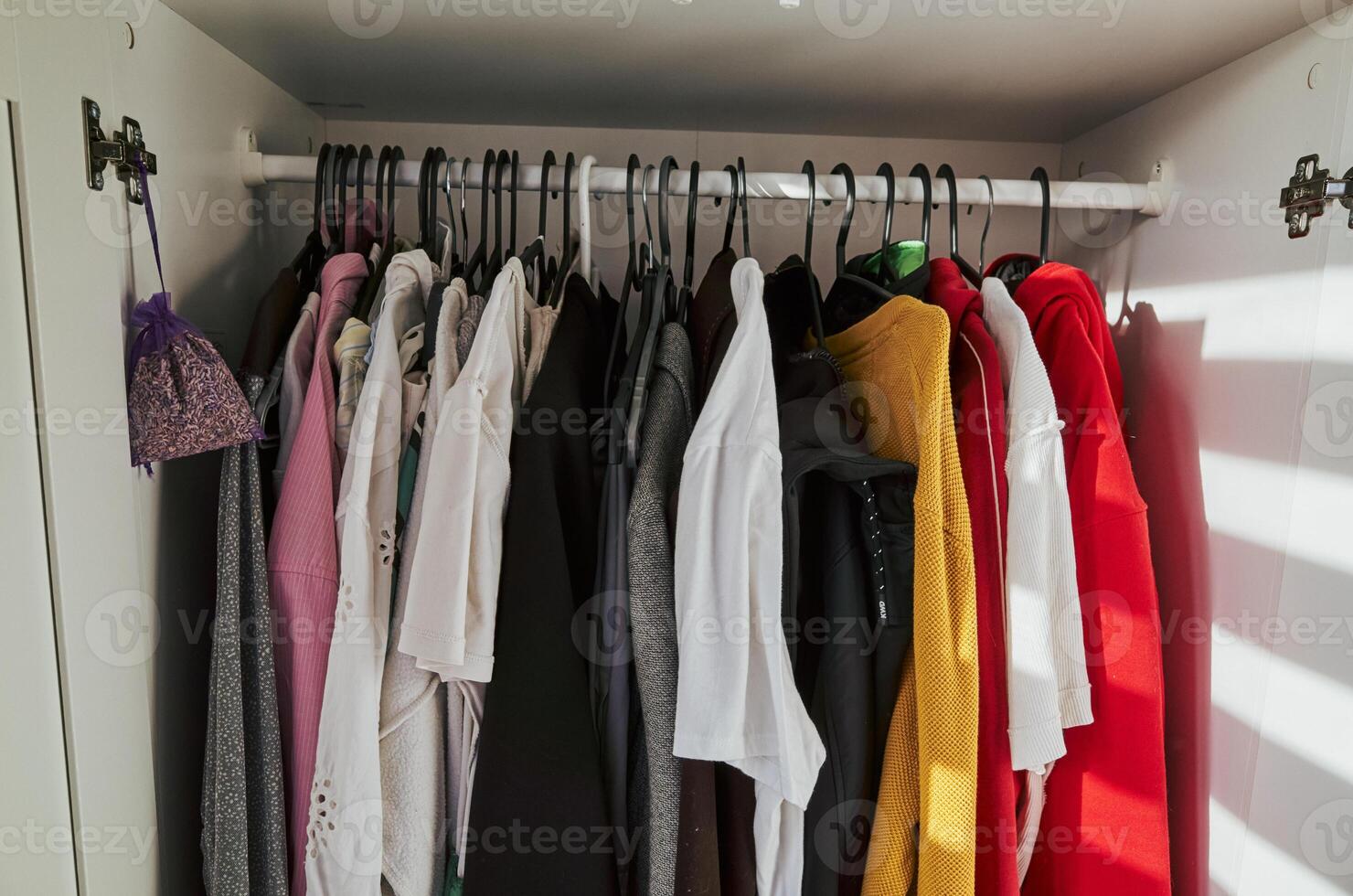 Closet full of clothes with a white shirt hanging on the left side photo