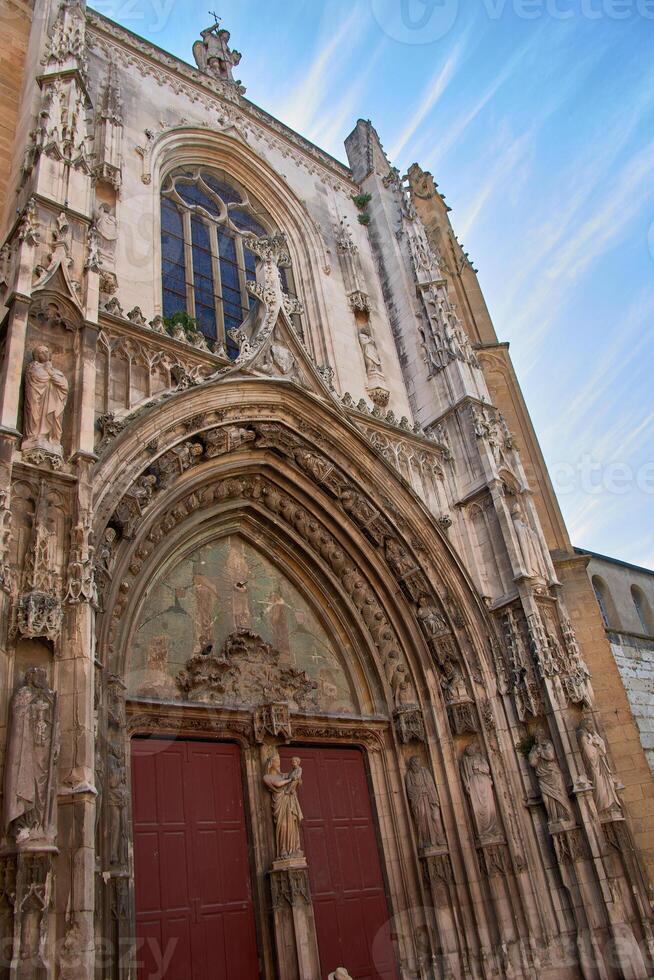 The imposing entrance of Saint Sauveur Cathedral, Aix-en-Provence, with its sculpted portal and stained-glass window. photo