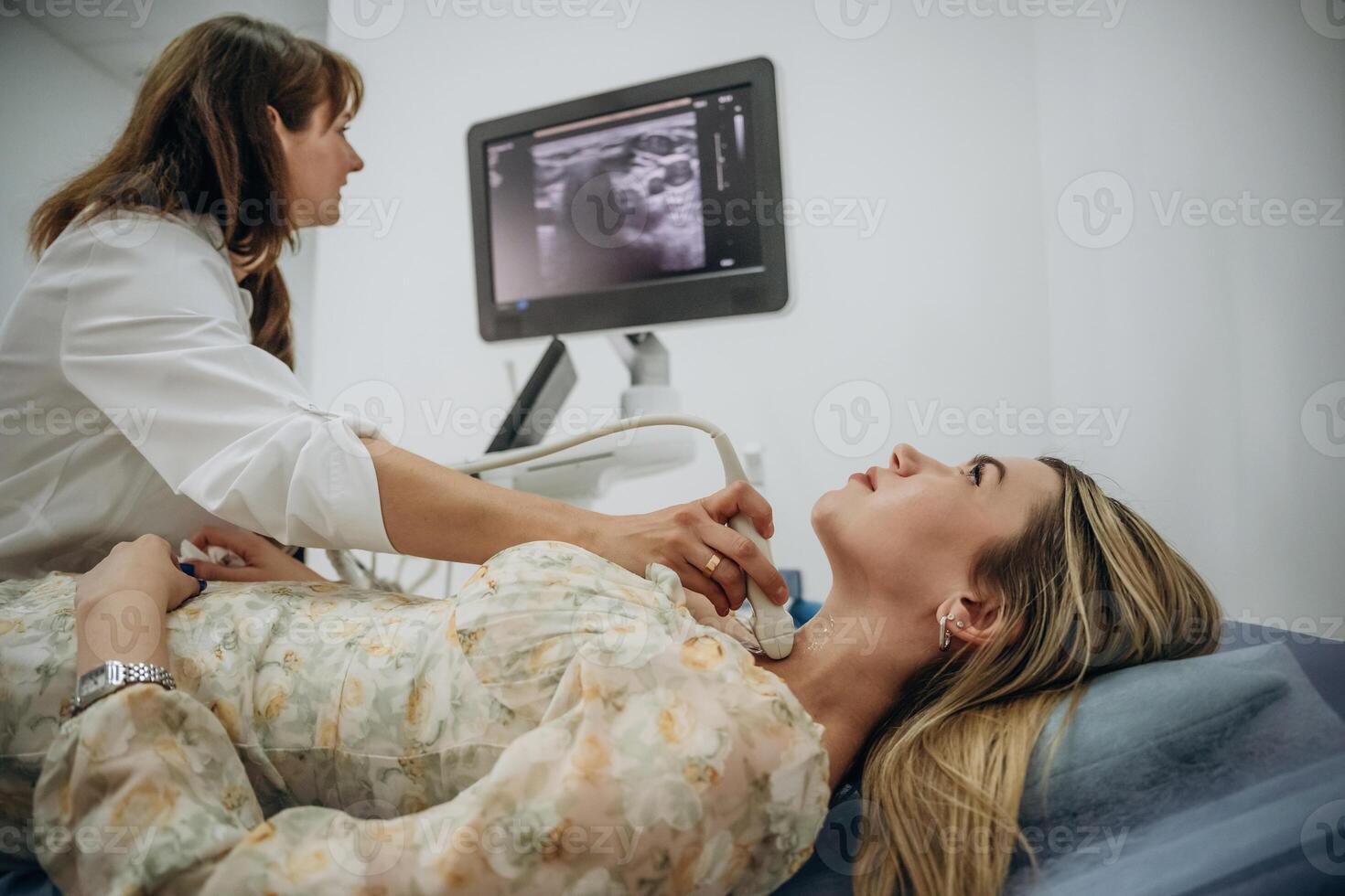 Woman, is lying down and undergoing ultrasonic test of the thyroid gland photo