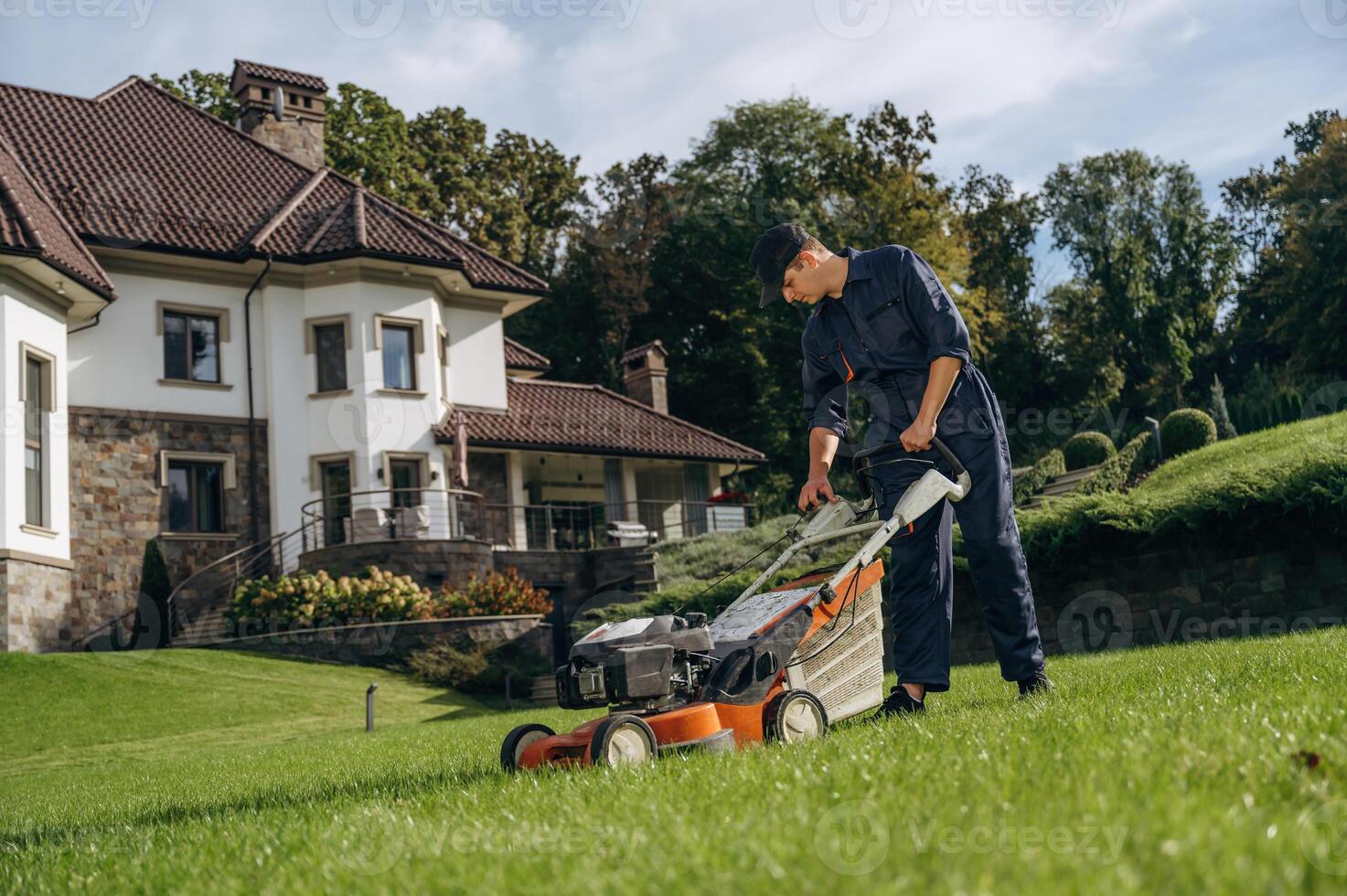 Cutting ,the, grass by lawn mover. Professional gardener is on the lawn photo