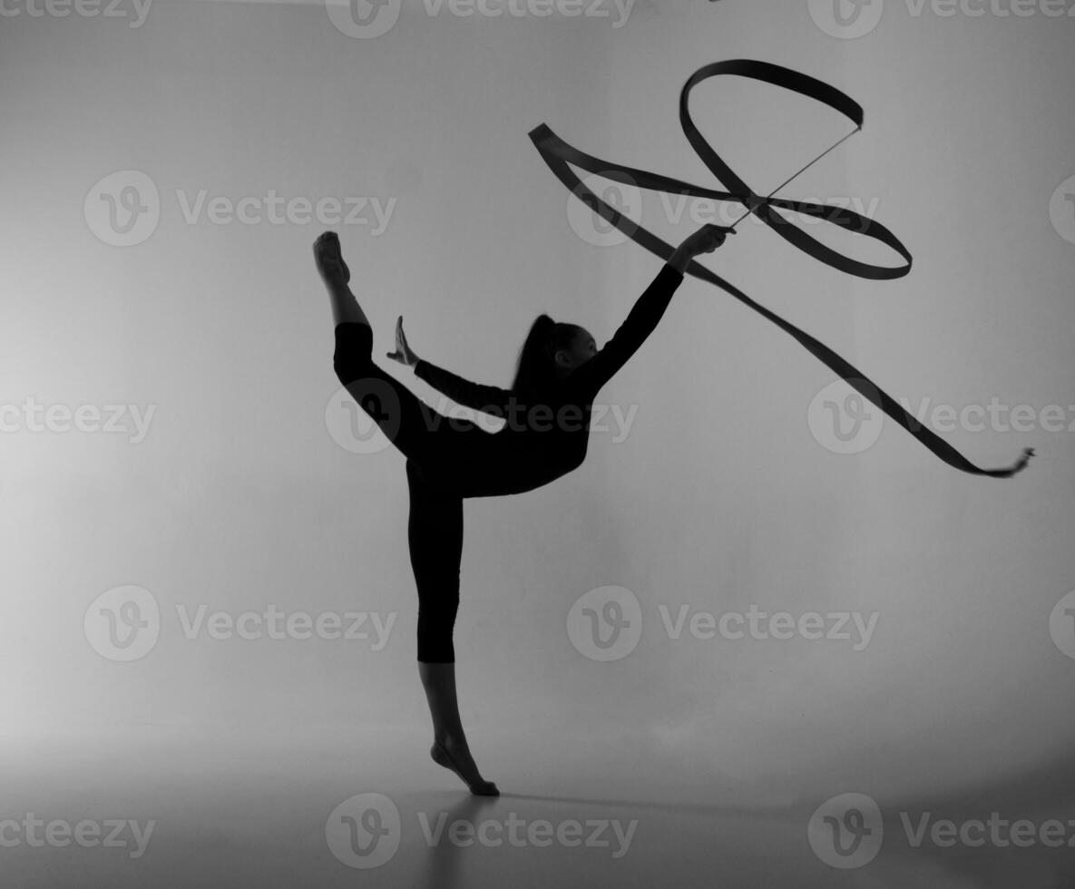 a girl from rhythmic gymnastics in bodysuit shows an exercise with a ribbon photo
