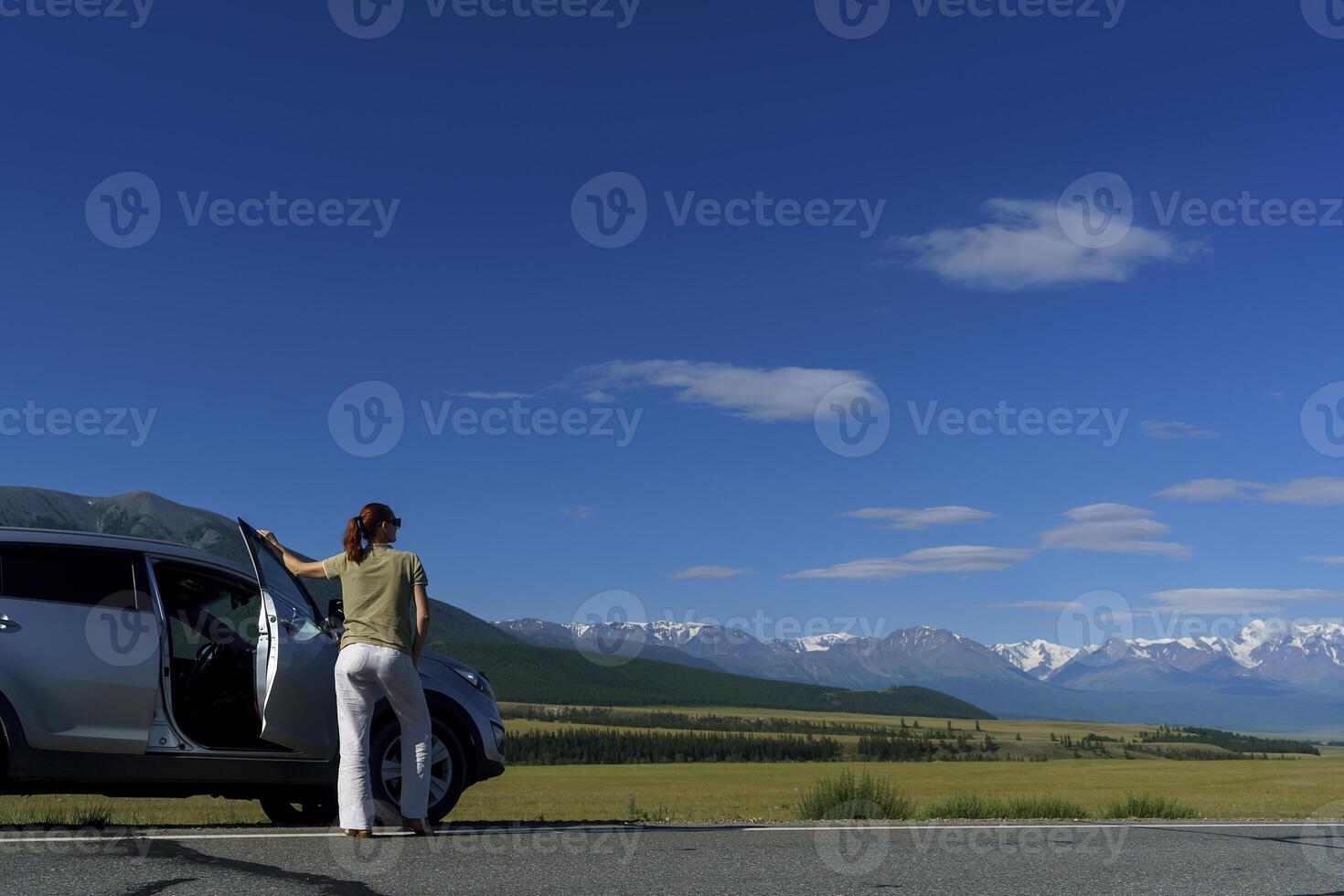 woman traveling by car stopped on the side of the road and admires mountains. photo