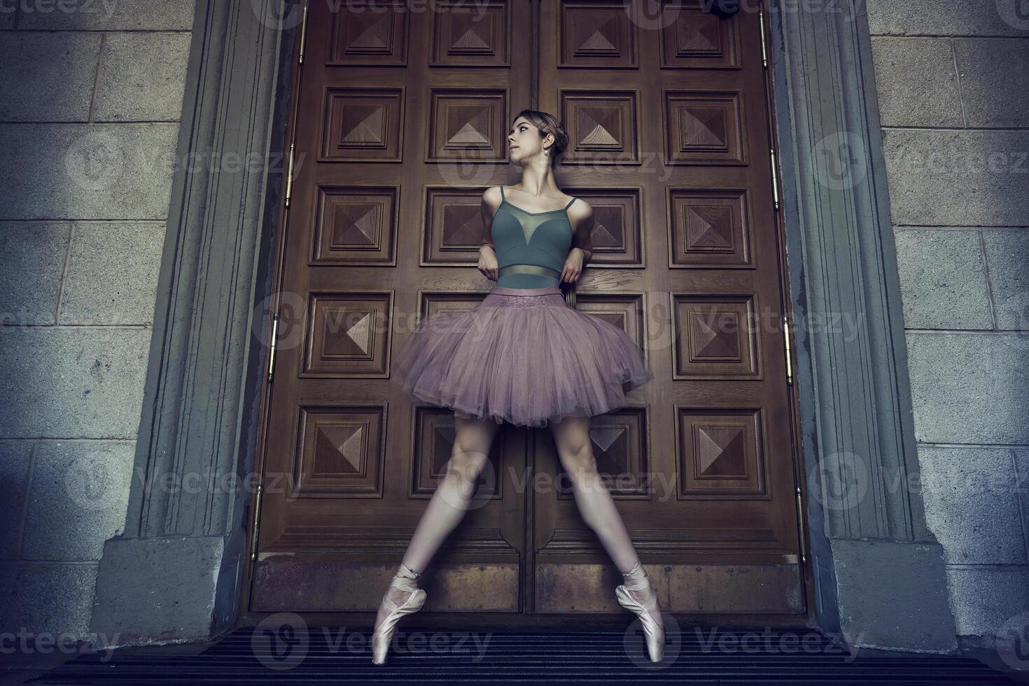 ballerina in tutu and pointe shoes shows ballet elements on the streets, on a summer day photo