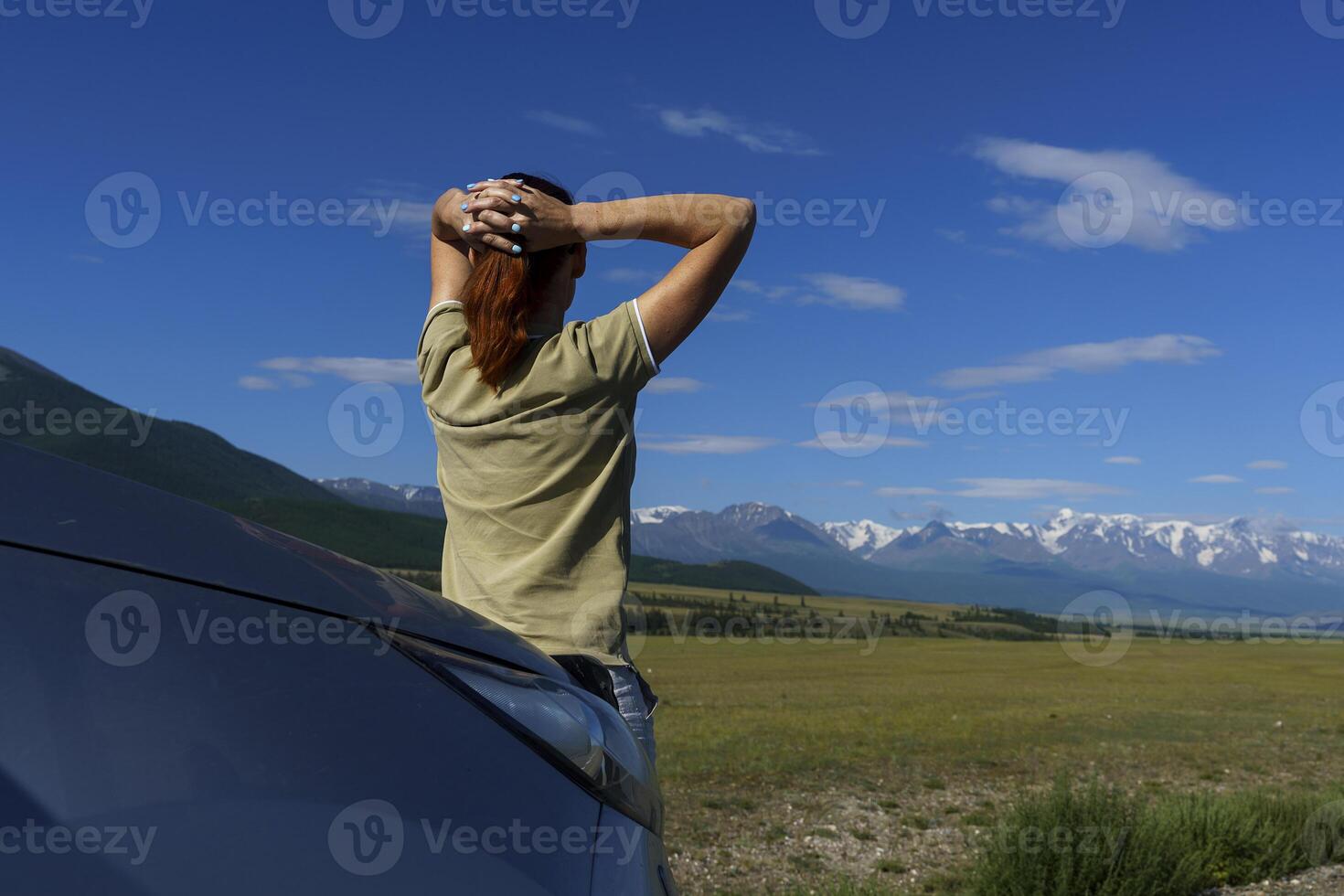 woman, traveling by car, stopped on the side of the road and admires mountains. photo