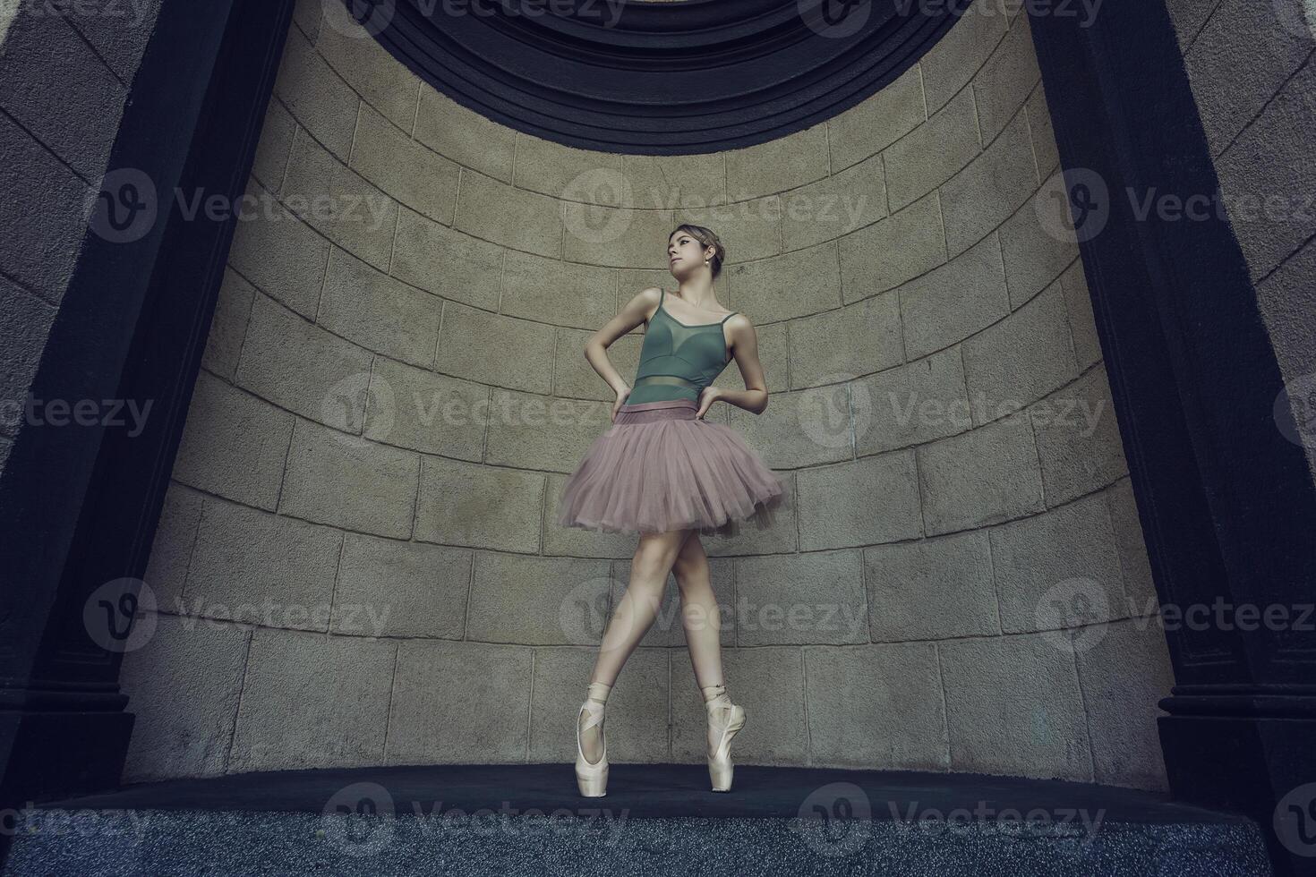 ballerina, in tutu and pointe shoes shows ballet elements on the streets, on a summer day photo