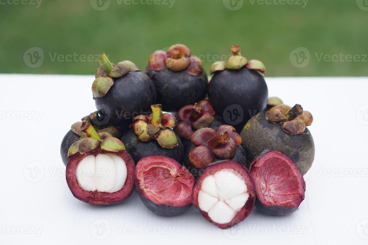 Fresh Thai mangosteens, some opened to reveal their juicy white flesh, are displayed on a clean surface. A seasonal tropical fruit known for its sweet taste, rich nutrients, and natural antioxidants. photo
